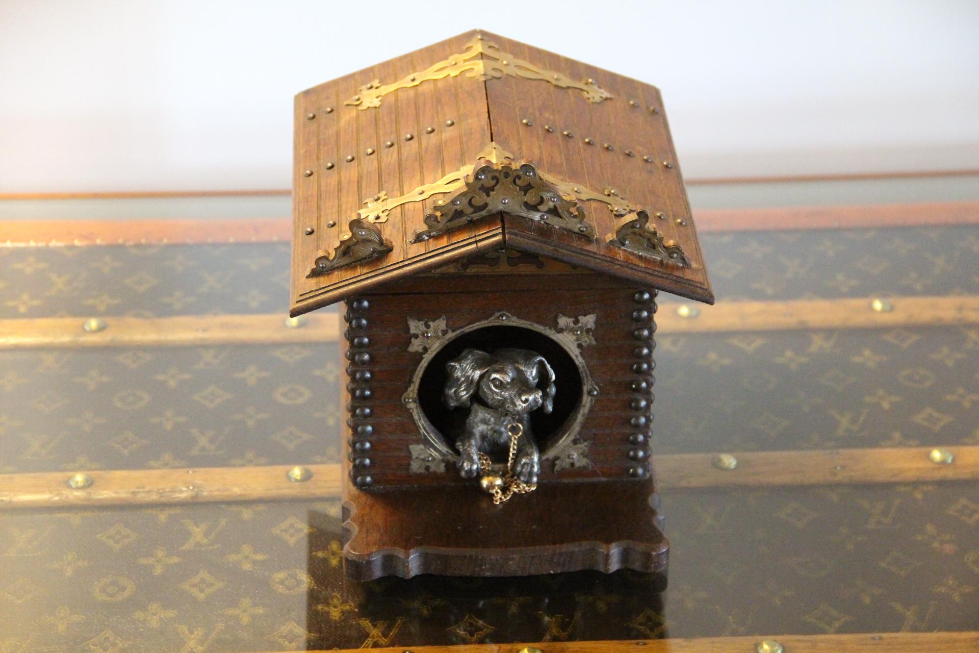 Cette boîte à cigares française très inhabituelle représente un chien en bronze argenté qui garde les cigares de son maître.Il se tient à la fenêtre de sa niche et au bout de sa chaîne se trouve la clé qui permet d'ouvrir la boîte à cigares.Mais