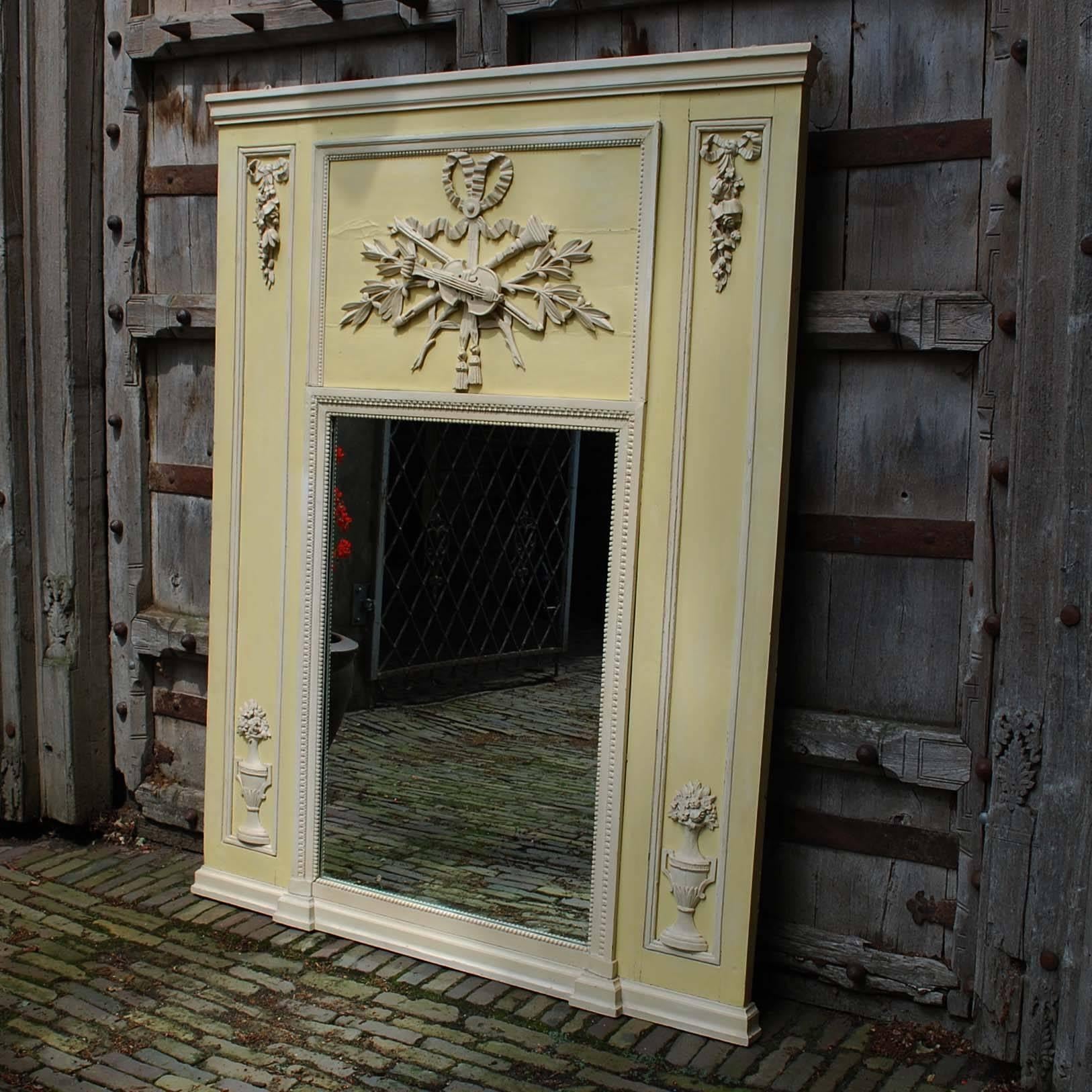 A French classical painted trumeau mirror with ribbon tied musical trophy and urns from the mid 19th century.
It features an authentic vertical mirror plate surrounded by a pearl beading. The mirror is beautifully adorned with a ribbon tied musical