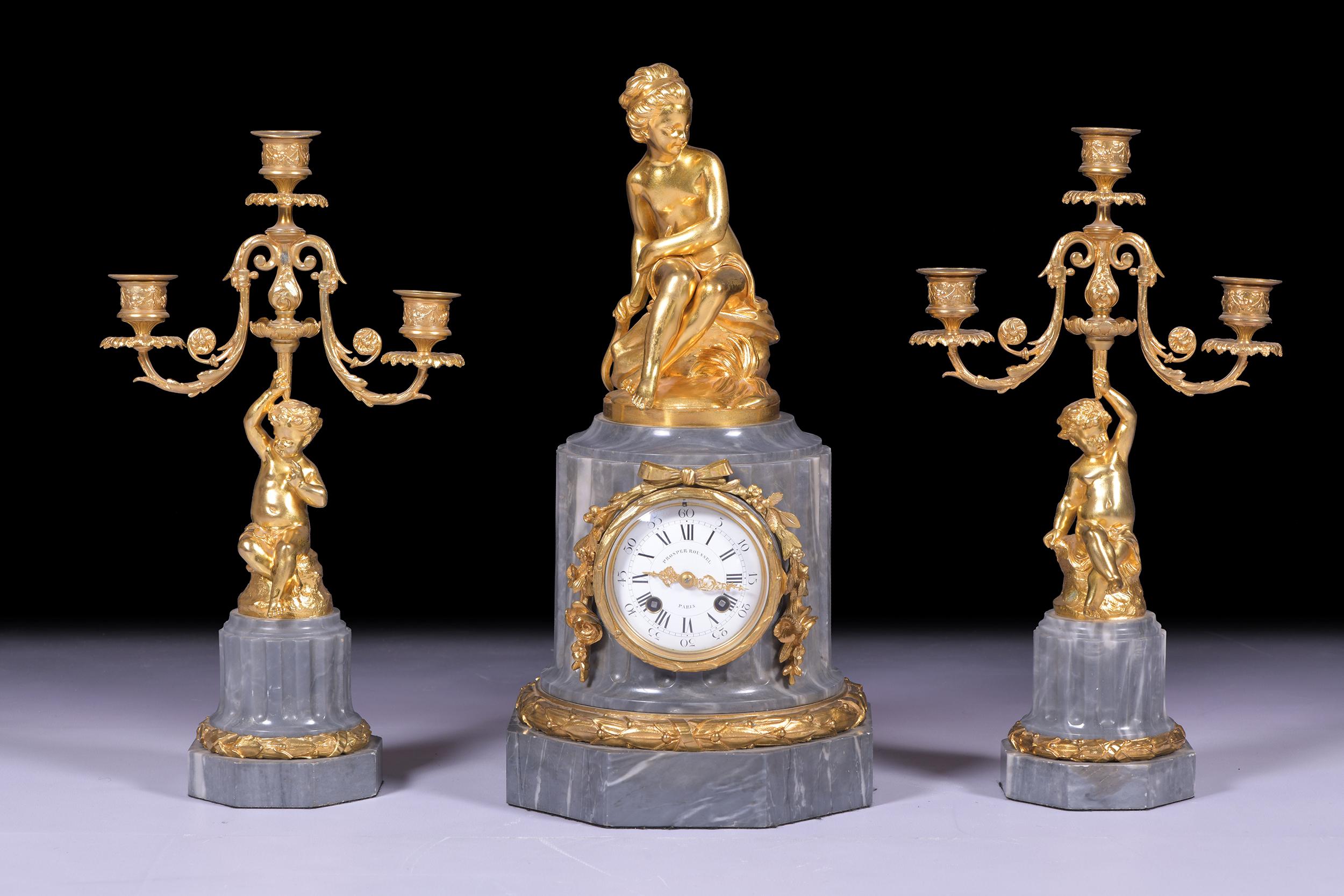 A stunning ormolu and onyx mantle clock with garniture. Surmounted by a seated cupid on a octagonal shaped base with a wreath border, twin barrel movement striking on a bell ,an enamel dial with the hours and minutes in Roman numerals respectively,