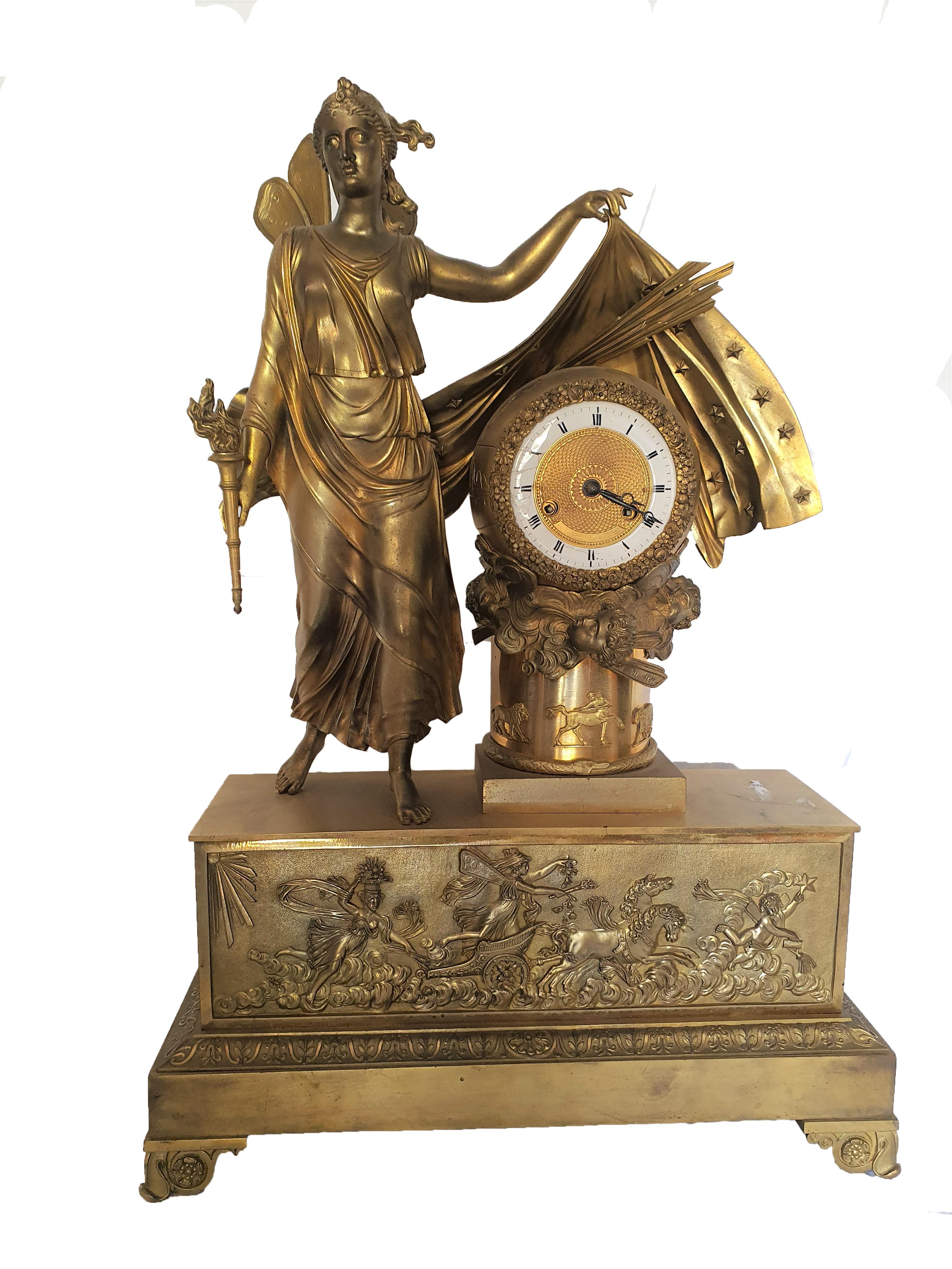 Elegant and important table clock in finely chiseled and gilded bronze. Finely chiseled bronze plate, depicting a winged lady and chariot, adorn the front part of the base, in the upper part we find a lady with a torch in her hand almost covering