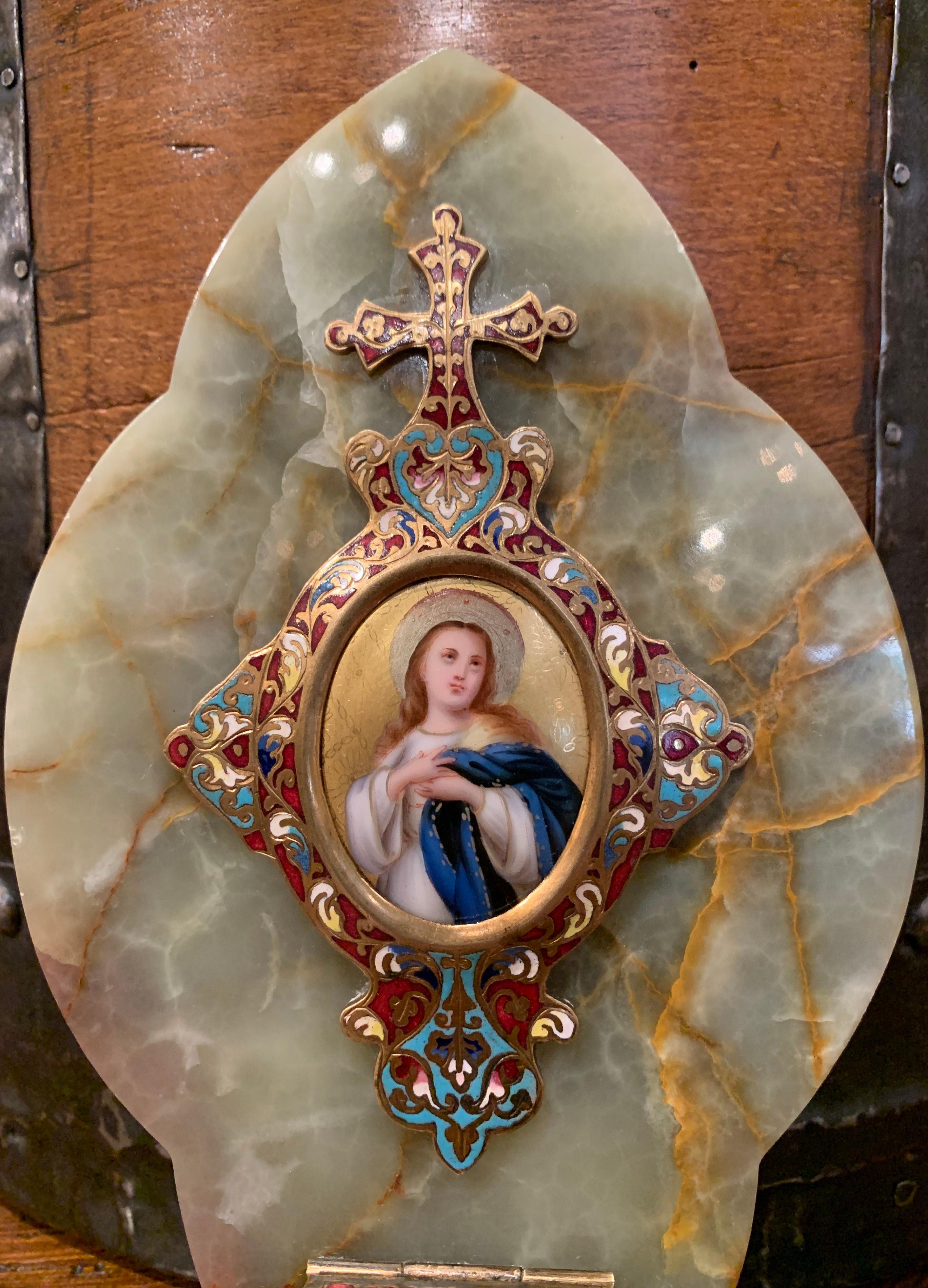 This religious marble and brass wall plaque with holy water recipient was created in France, circa 1880. Oval in shape, the antique piece features beautiful, intricate cloisonné work with enamel, stone and bronze; it is embellished with a hand