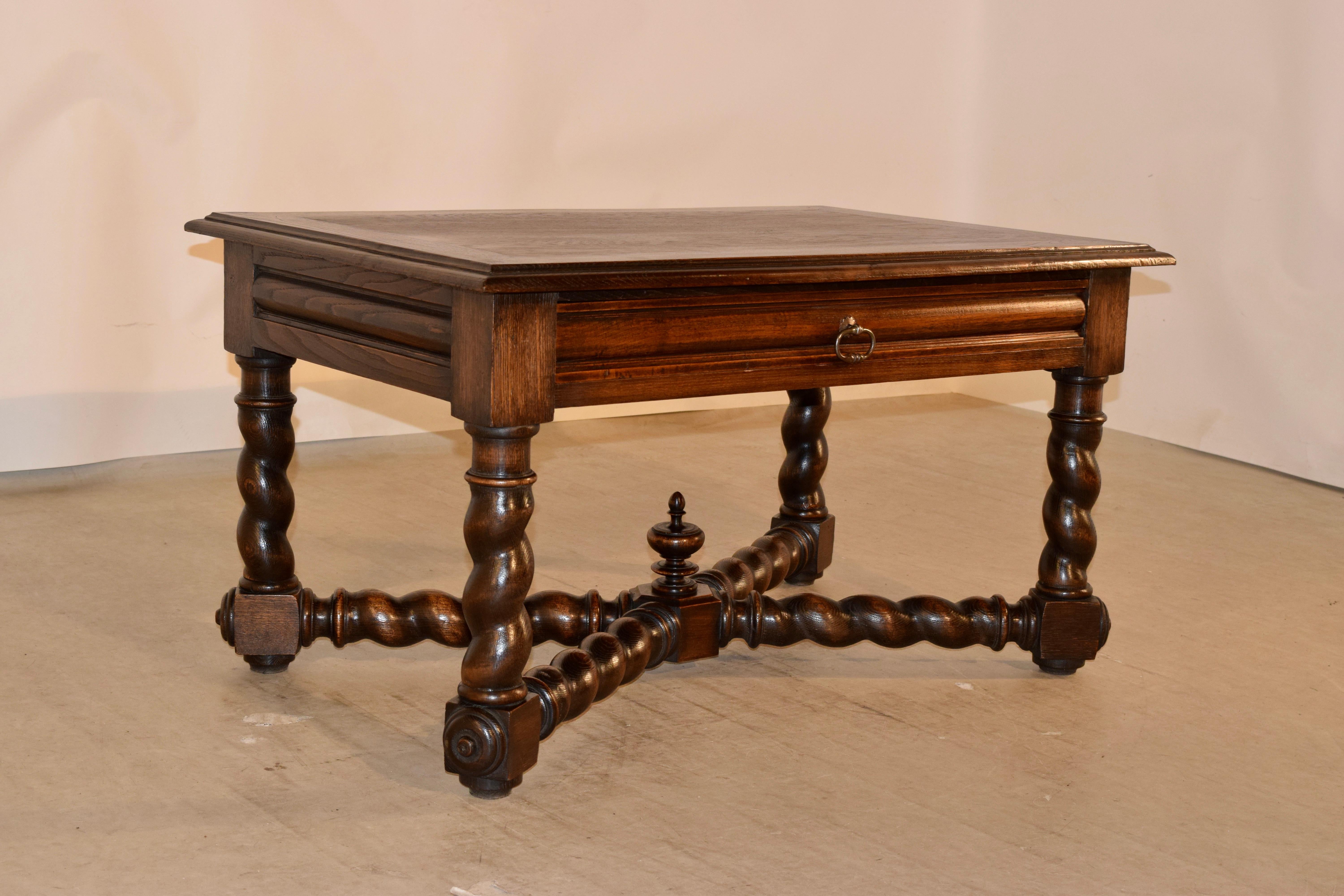 19th century coffee table from France made from oak. The top is banded and has a beveled edge on all four sides. The apron is simple and includes a single drawer. The table is supported on hand-turned barley twist legs, joined by matching cross