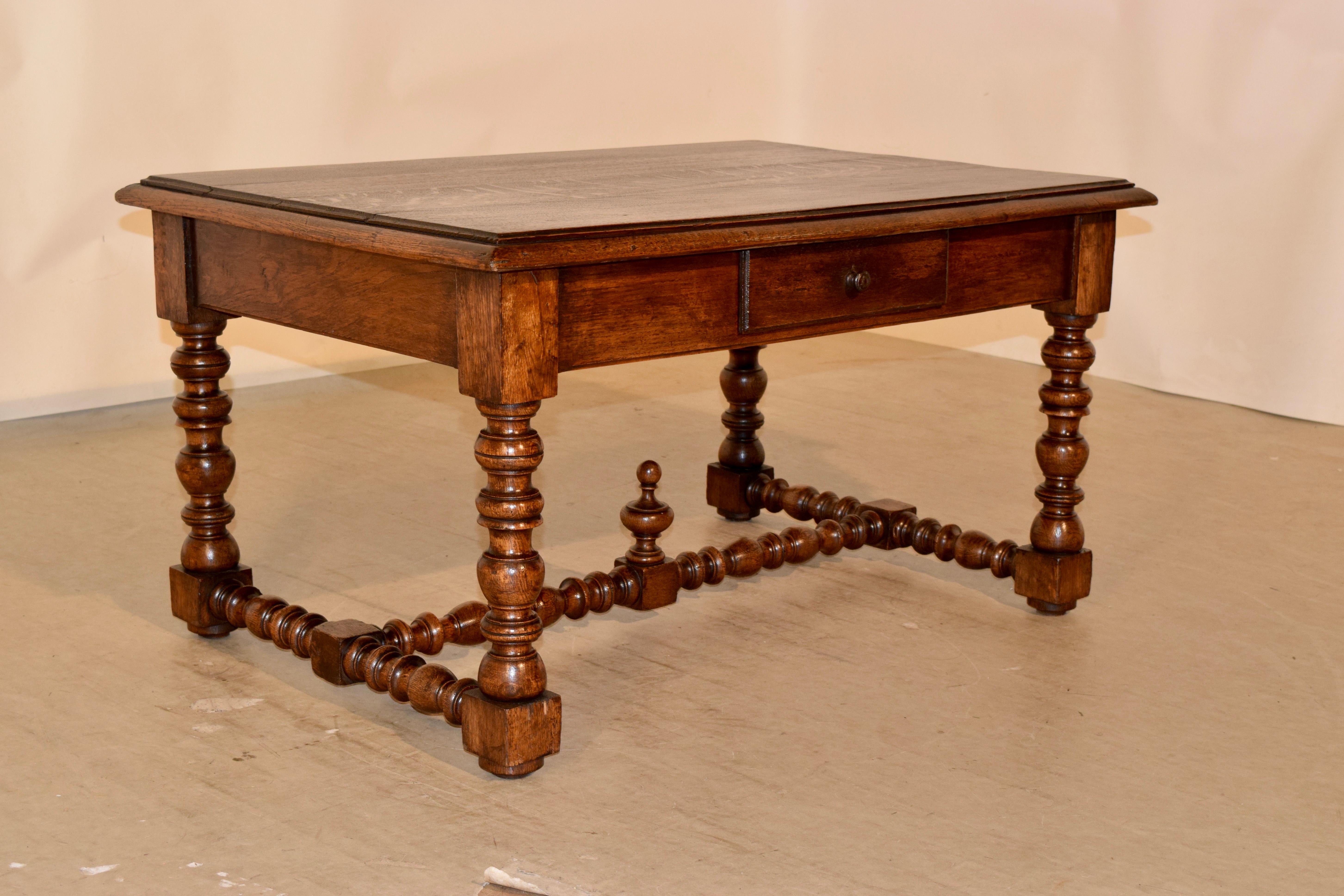 19th century French coffee table made from oak. The top has a molded and beveled edge, following down to a simple apron containing a single drawer. The table is supported on lovely hand turned legs which are joined by turned stretchers, and finished