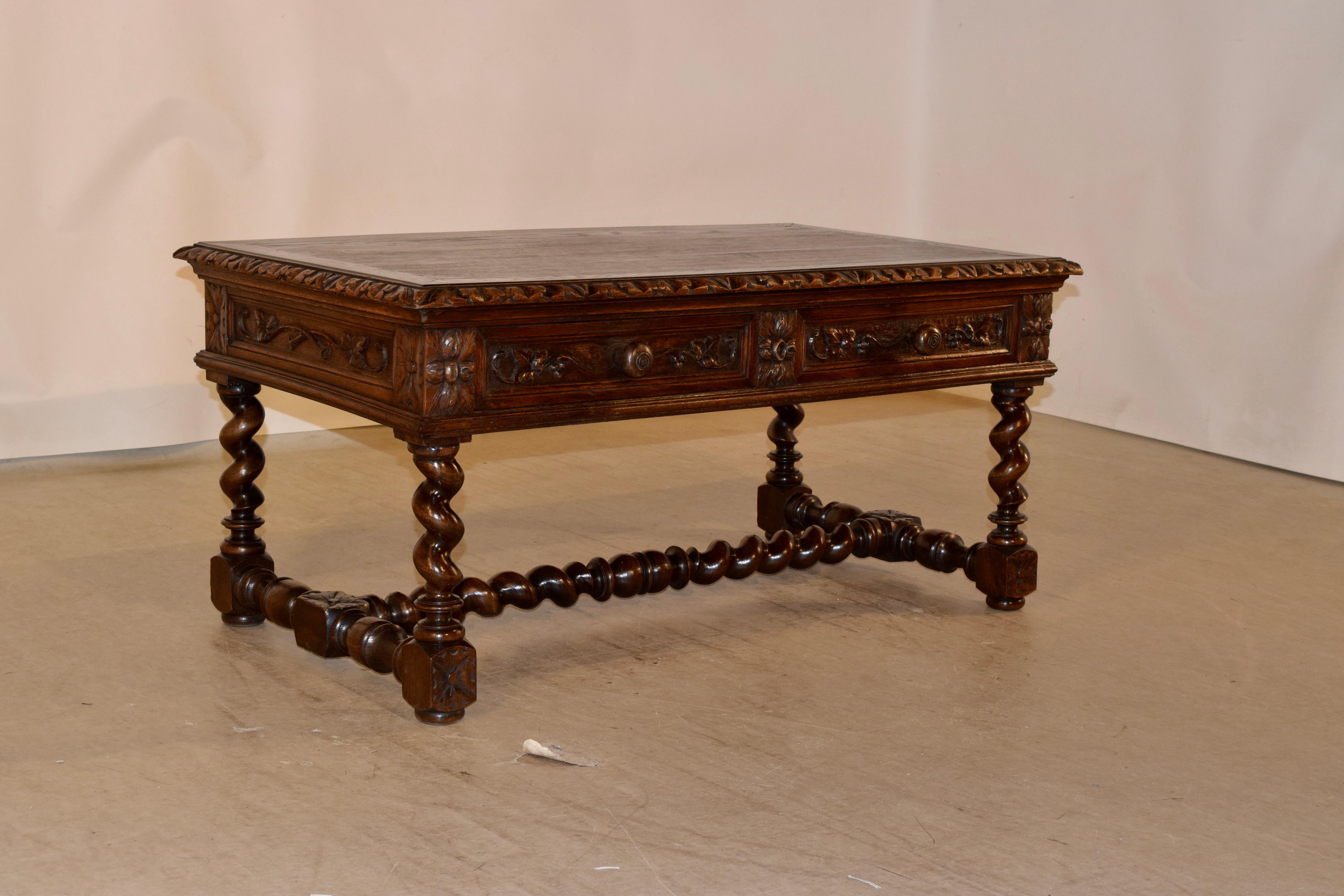 19th century coffee table from France made from oak. The top is banded around the edge and has a beveled and carved decorated edge as well. The apron is paneled and has two drawers with carved decoration in the front, over hand-turned barley twist
