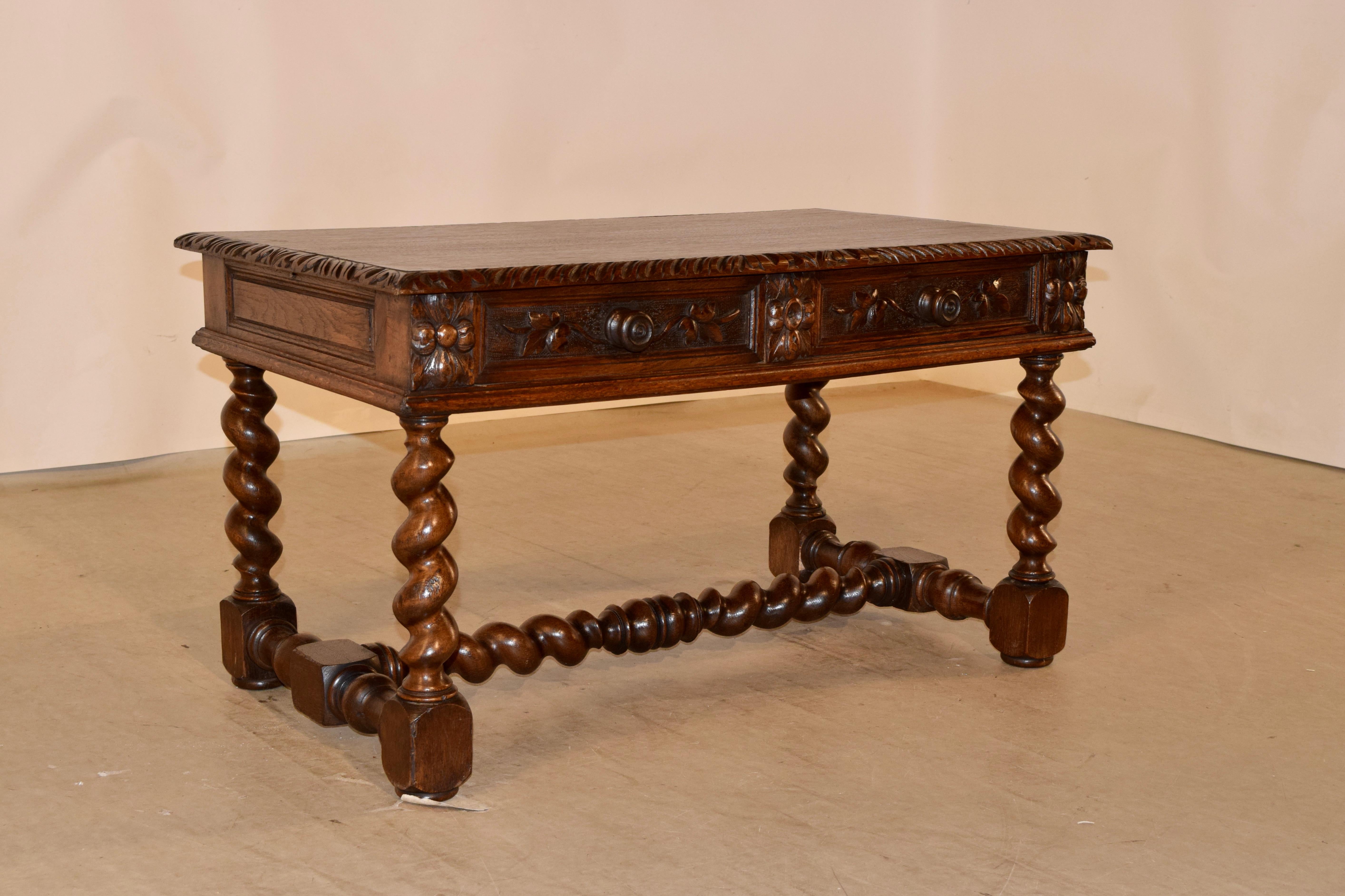 19th century coffee table from France made from oak. The top has a beveled and carved decorated edge around the top, following down to a paneled apron on the sides and two drawers with molded edges and carved decoration in the front, over