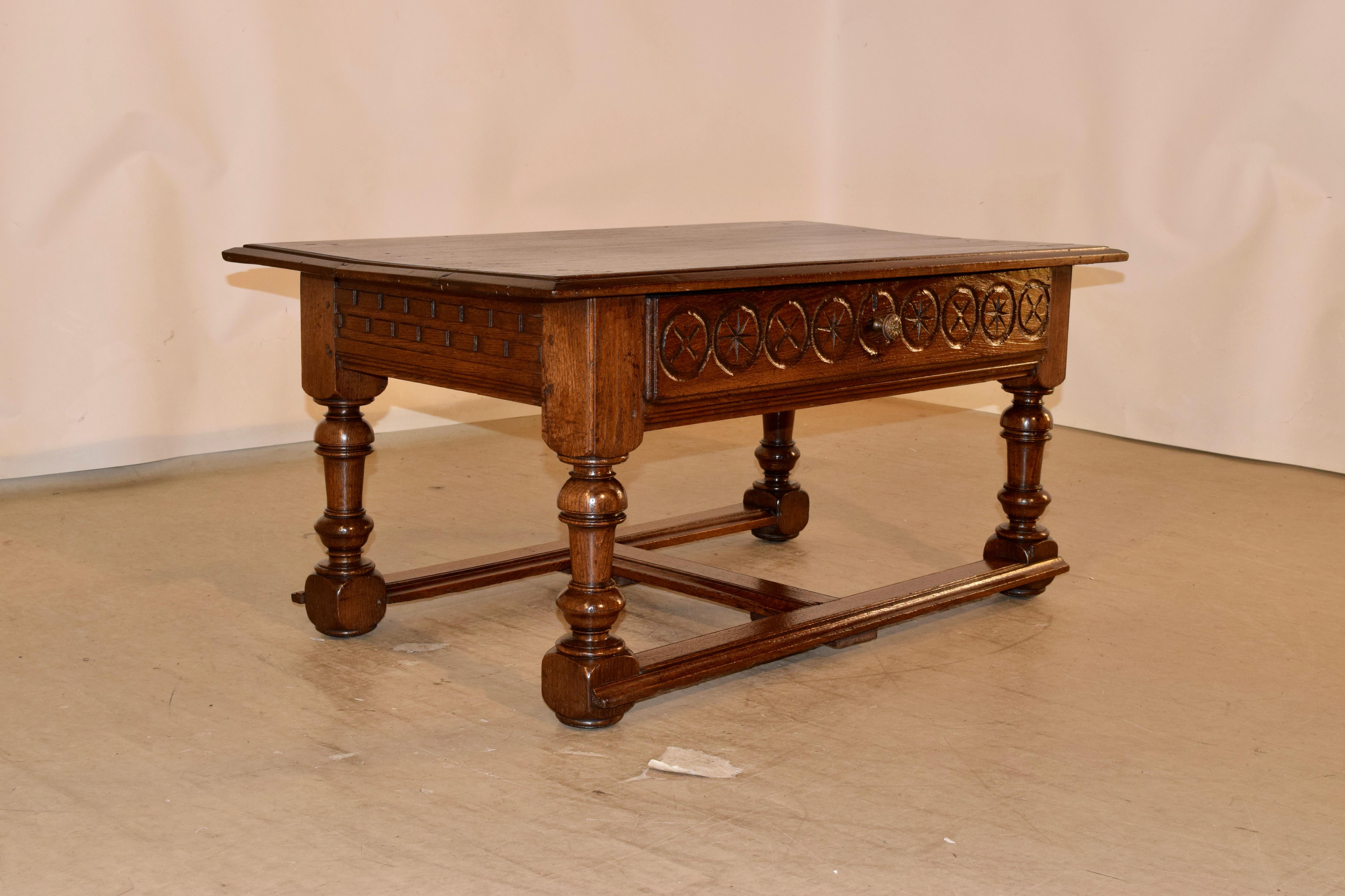 19th century oak coffee table from France with a three plank top which has a beveled edge, following down to a wonderfully hand carved decorated apron which contains a single drawer in the front. The table is supported on hand turned legs, joined by