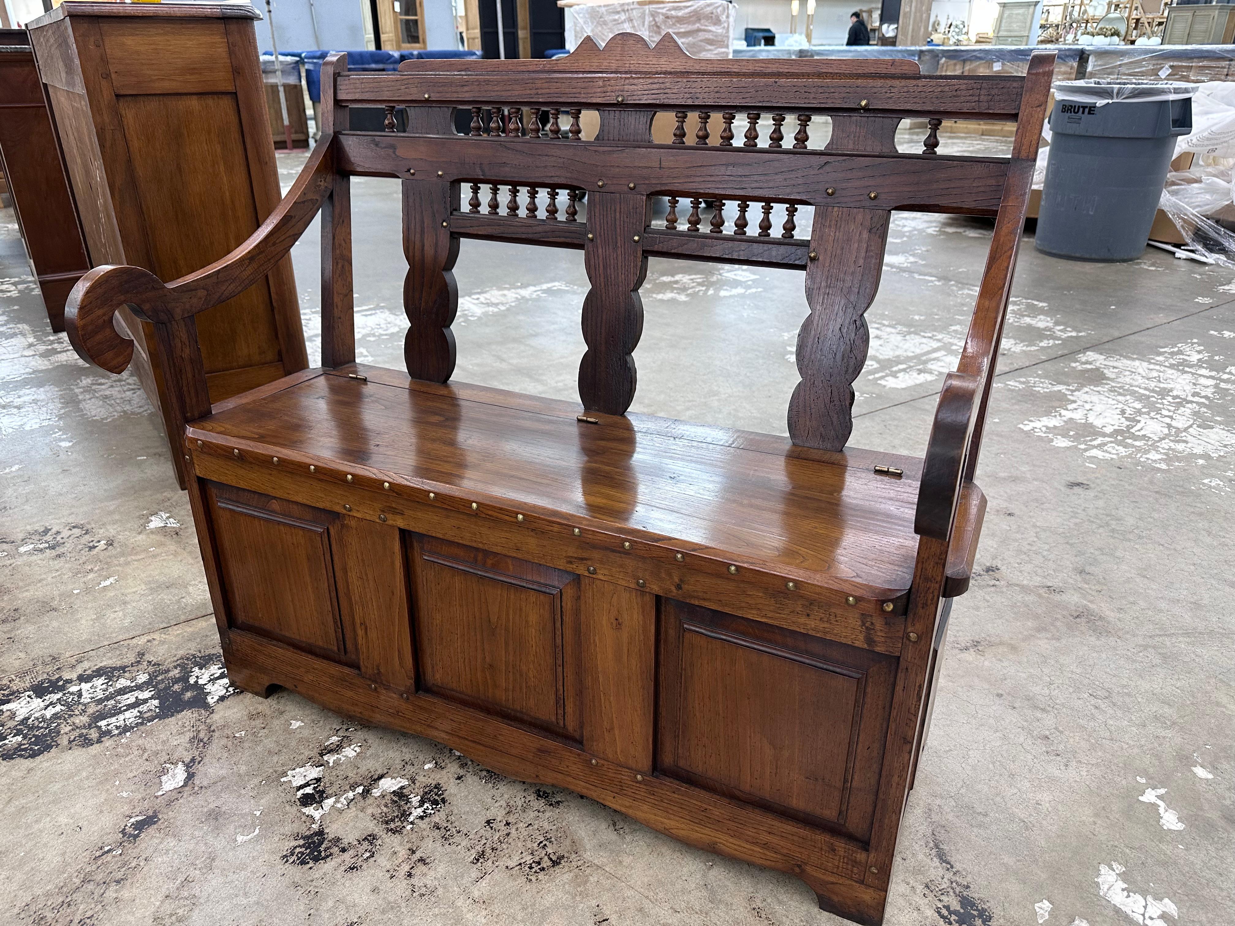 This is an amazing antique piece! Dating to the early 19th century, this bench/coffer combo has a simple but appealing design. Slightly inset drawer panels, curved back with turned spindles, and gently curving arms are nicely accented by brass nail