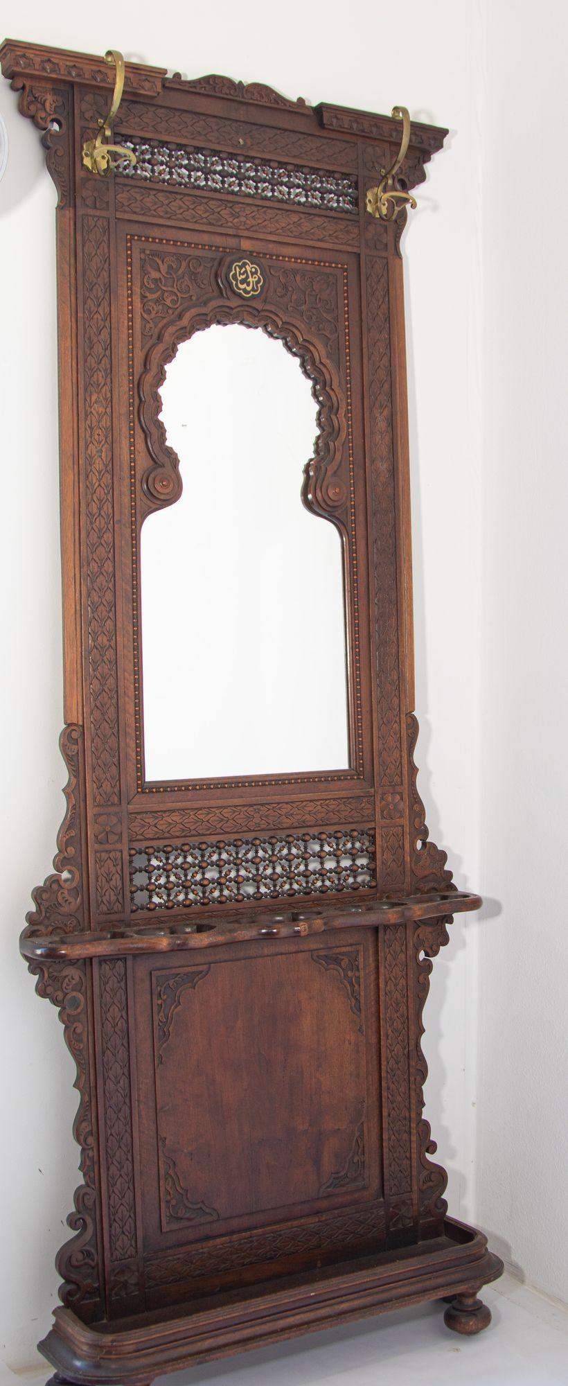 19th Century French Colonial Moorish Style Hall Tree.
Moorish hall tree with mirror 2 brass coat hooks, heavily carved wood with leafy scrollwork and Middle Eastern fret work.
This elegant antique Gothic coat rack with umbrella and cane holder was