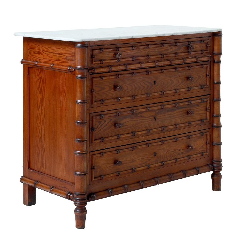 An 19th-century French commode featuring a white marble top and a faux bamboo carved wood frame. Crafted from rich, warmly toned wood, this commode has four spacious drawers, each adorned with delicate, carved faux bamboo trim and small turned