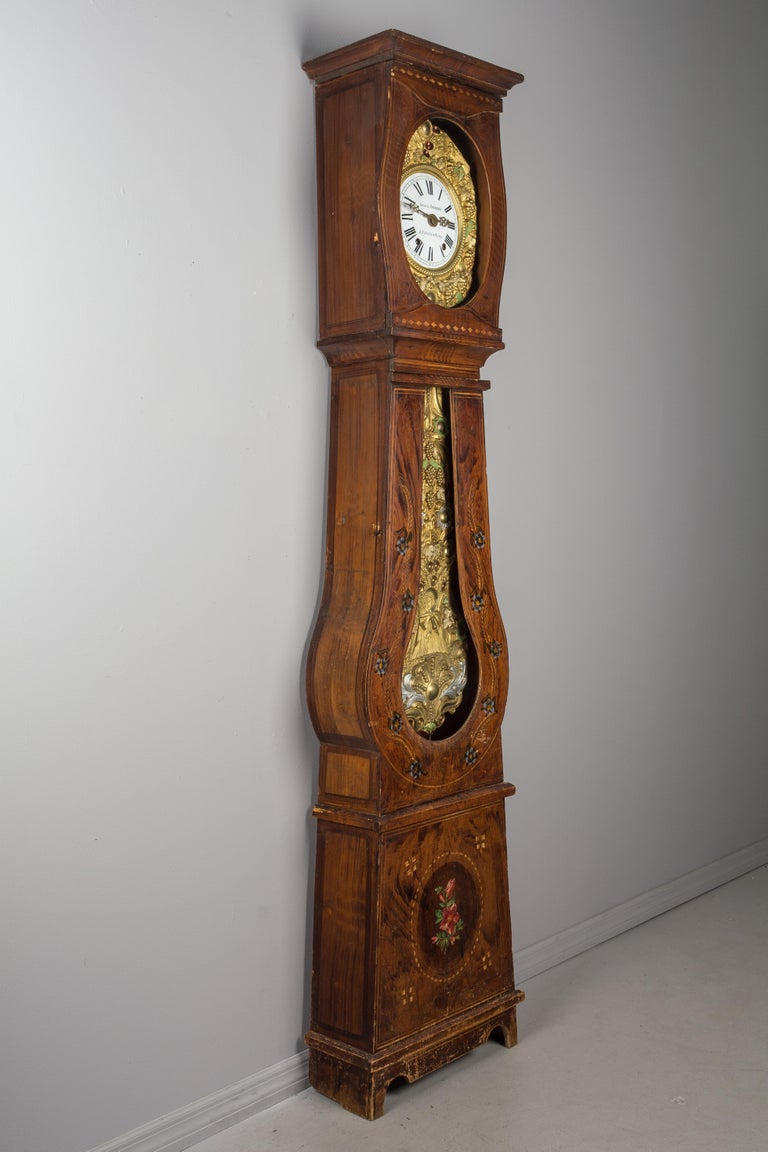 A 19th century Country French comtoise, or grandfather clock, with polychrome painted pine case and embossed brass pendulum. Original seven day Morbier movement, professionally cleaned and in working order, having an enamel face signed by the