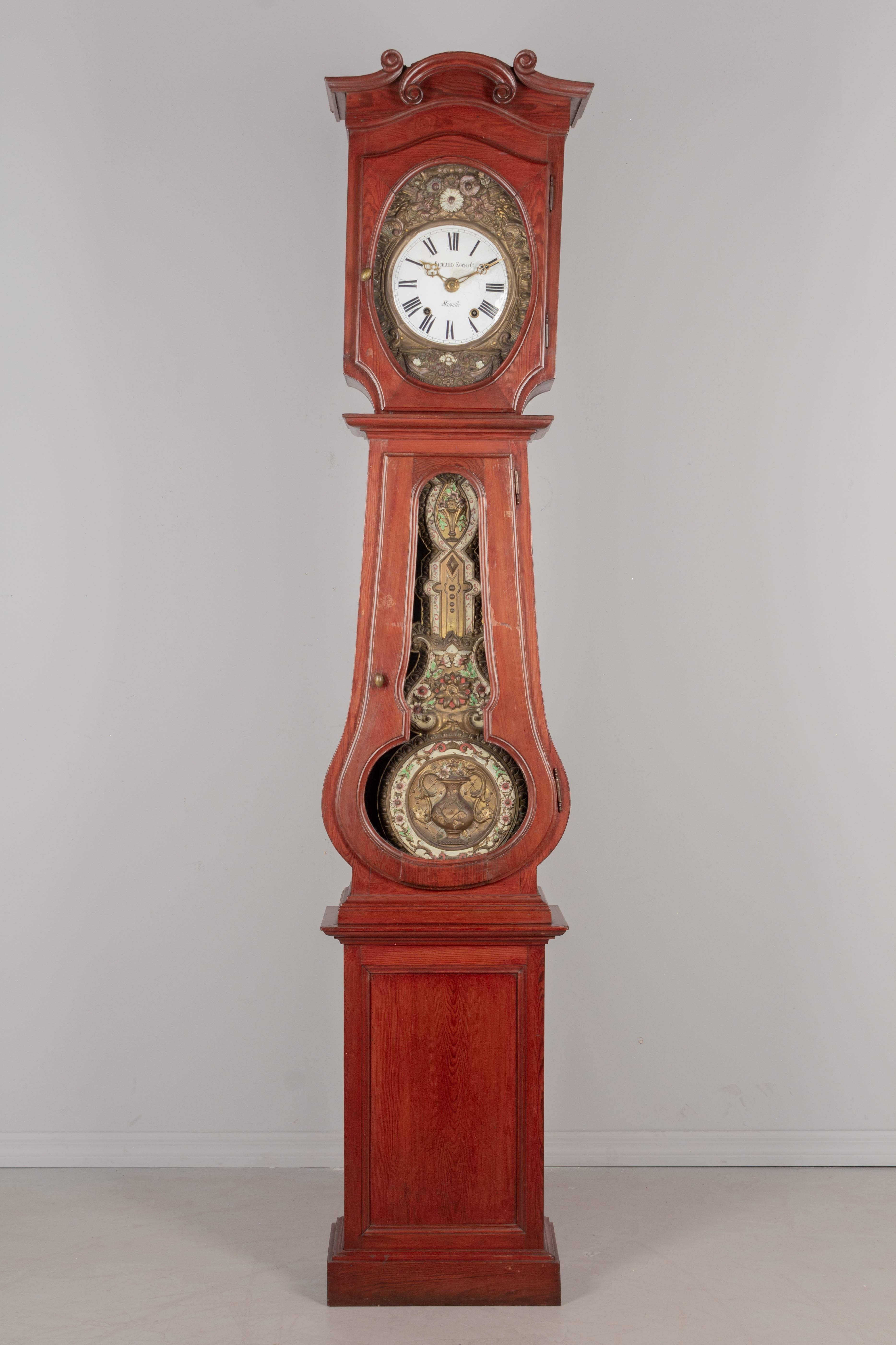 Eine französische Standuhr aus dem 19. Jahrhundert mit Kieferngehäuse und geprägtem Messingpendel. Das Gehäuse stammt aus der Normandie (ca. 1900-1920) und das Uhrwerk aus Marseille (ca. 1880-1900). Das Sieben-Tage-Morbier-Uhrwerk wurde