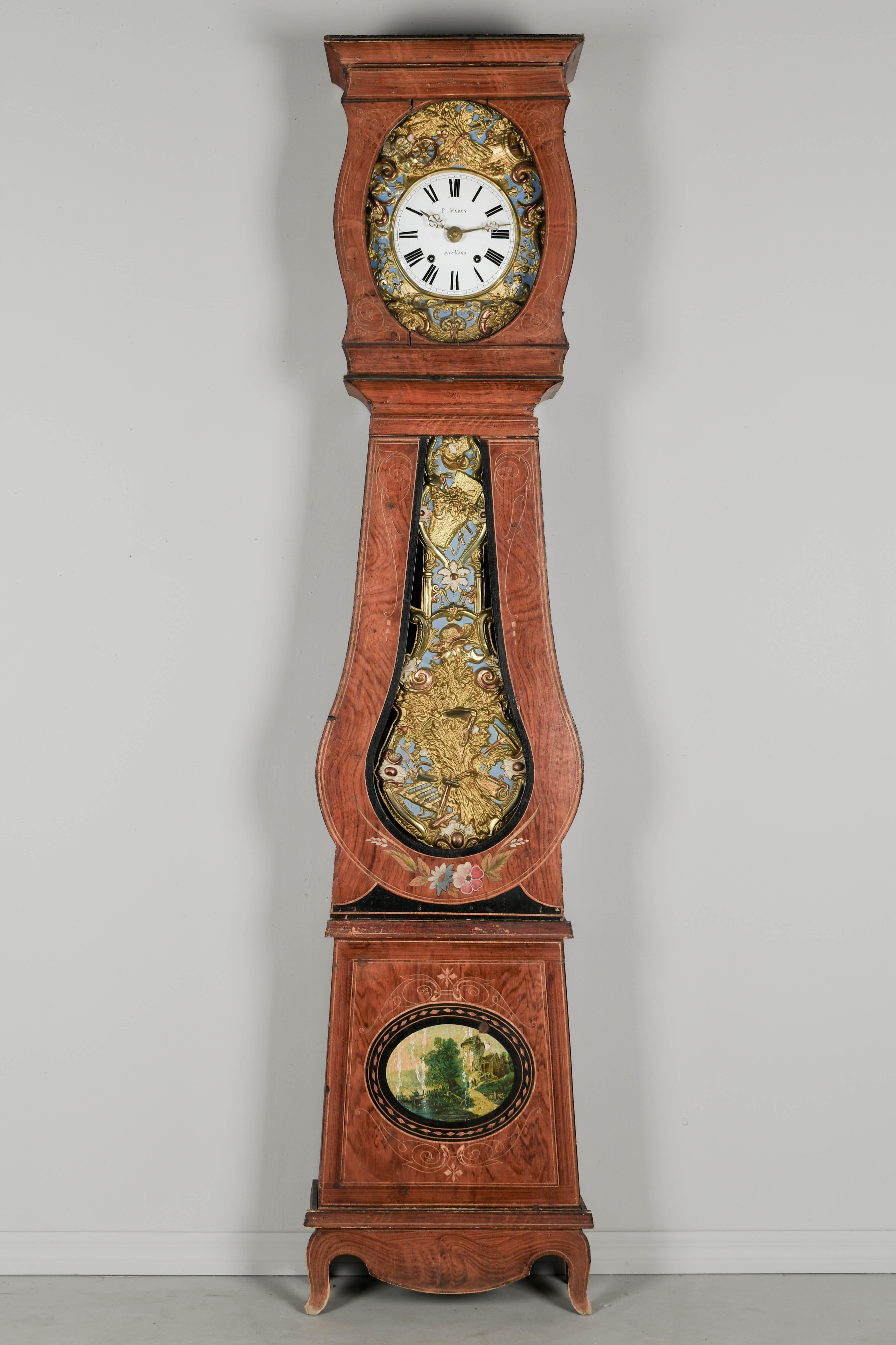 A 19th century Country French comtoise, or grandfather clock, with polychrome painted pine case and embossed brass pendulum. Seven day Morbier movement, professionally cleaned and in working order. Enamel face signed by the clockmaker, P. Marcy and