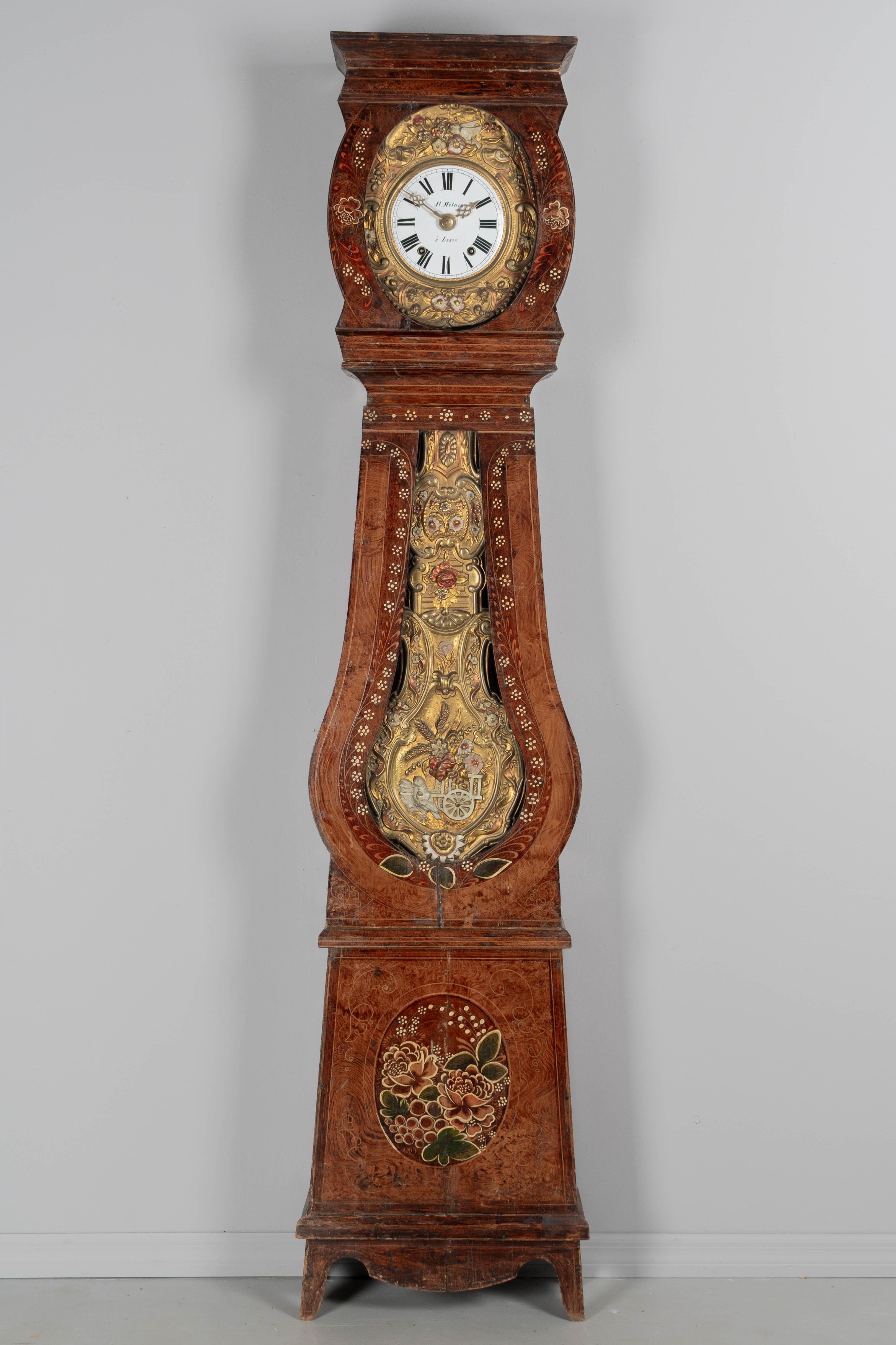 A 19th century Country French comtoise, or grandfather clock, with polychrome painted pine case and embossed brass pendulum. Seven day Morbier movement, professionally cleaned and in working order. Enamel face signed by the clockmaker, Al. Métais