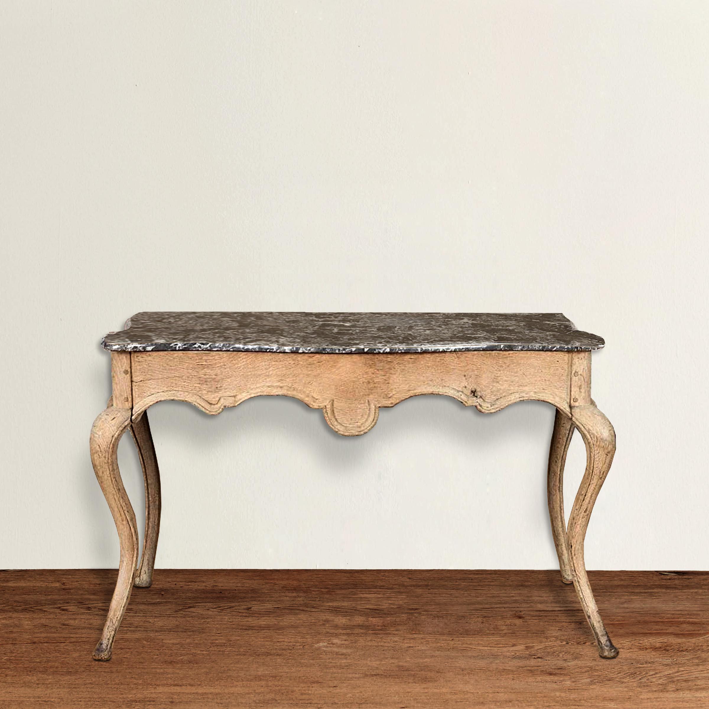An incredible ornamental yet not ostentatious 19th century French Louis XVI-style unfinished oak console table with a scalloped apron, exaggerated and sexy tapered cabriole legs, and an active black and white marble top with an ogee edge. Très chic!