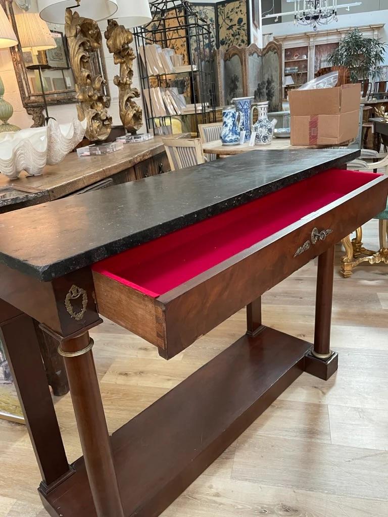 19th c. French Bronze Mounted Figured Mahogany Console or Hall Table, with heavy black stone top, single red velvet lined drawer, set on round column form legs, 34