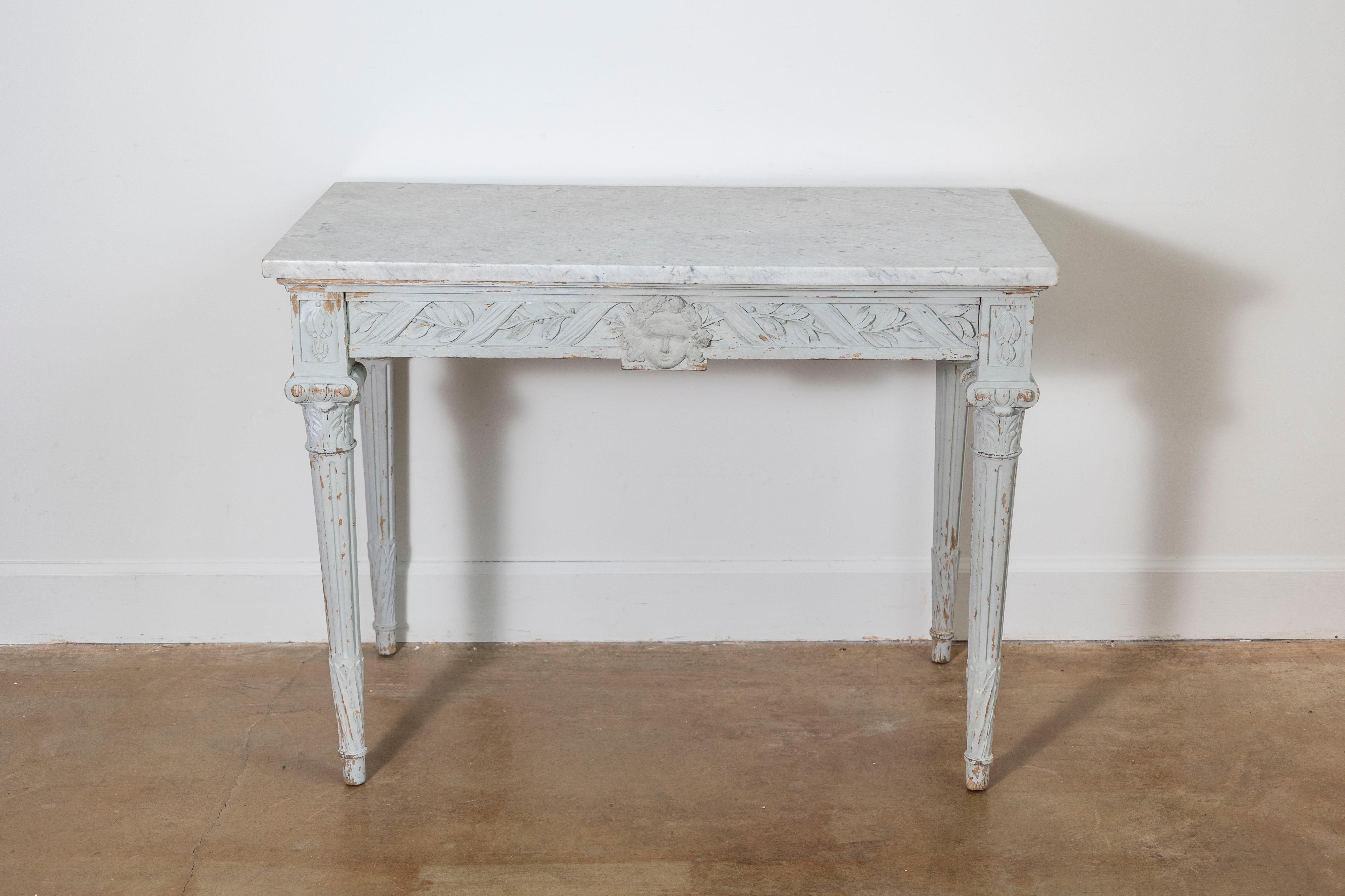This 19th-century French console table exudes timeless elegance, showcasing the craftsmanship of the Louis XVI style. The table features a rectangular marble top, adding a touch of sophistication and durability, supported by a delicately carved