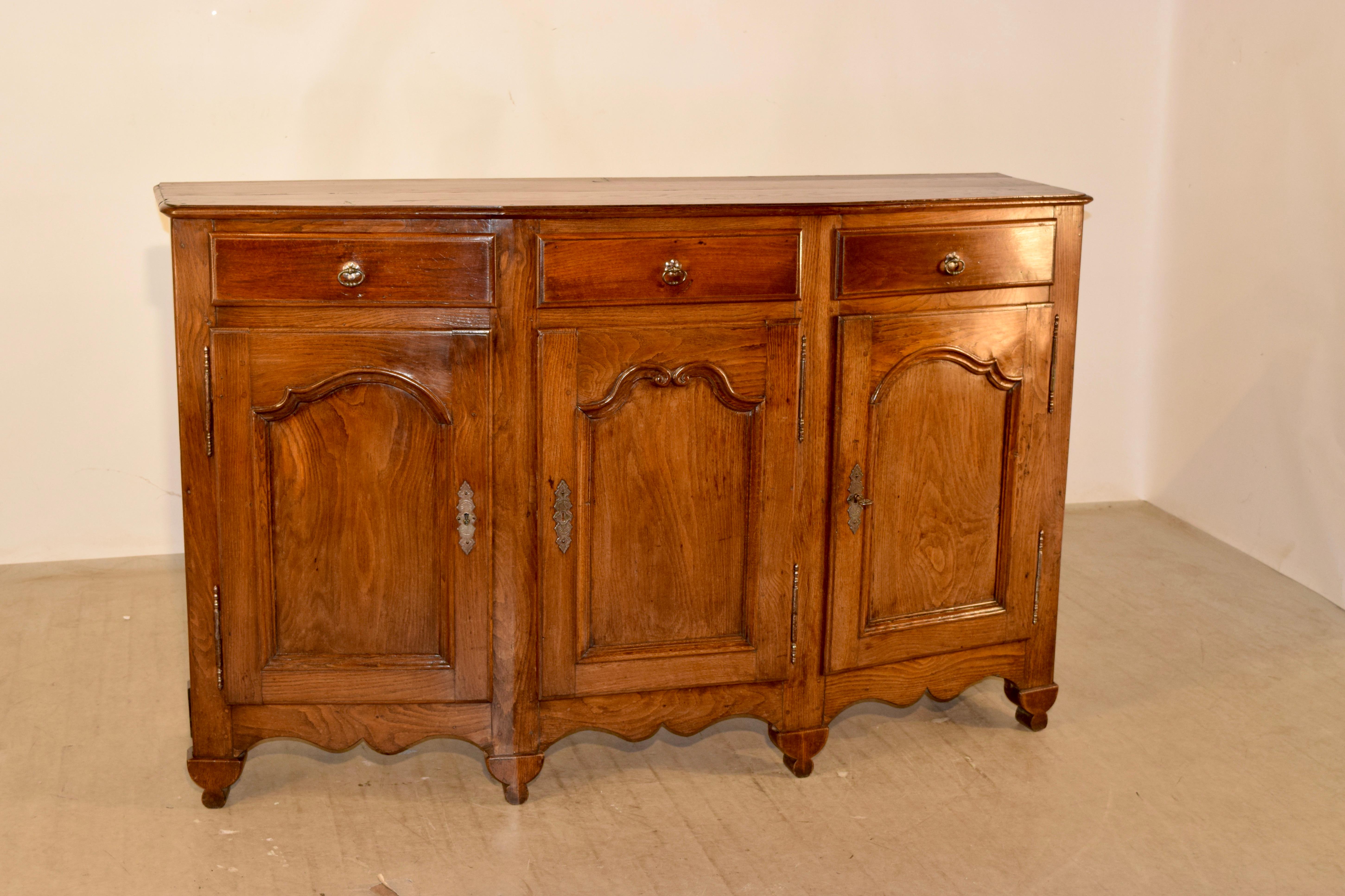 19th century oak enfilade from France in a wonderfully convex shape. The top has a beveled edge and follows down to simple sides. There are three drawers, all with beveled edge detail over three raised paneled doors in the front, which open to