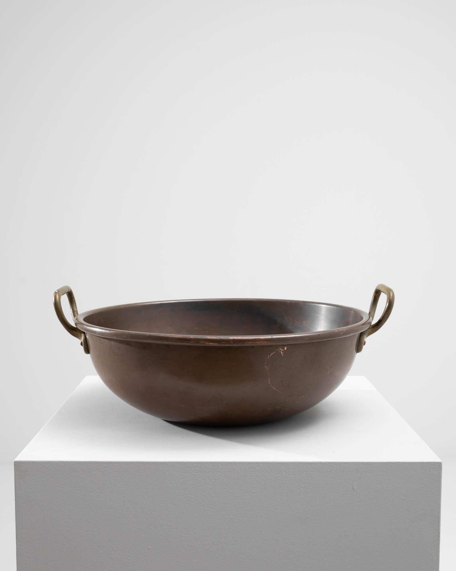 A copper bowl from the turn of the century Belgium. One of the best metals for conducting heat evenly, copper has been used for sauces, jams and marmalade making for centuries. A round shape, with upraised handles; the rich, rosy tone of the metal
