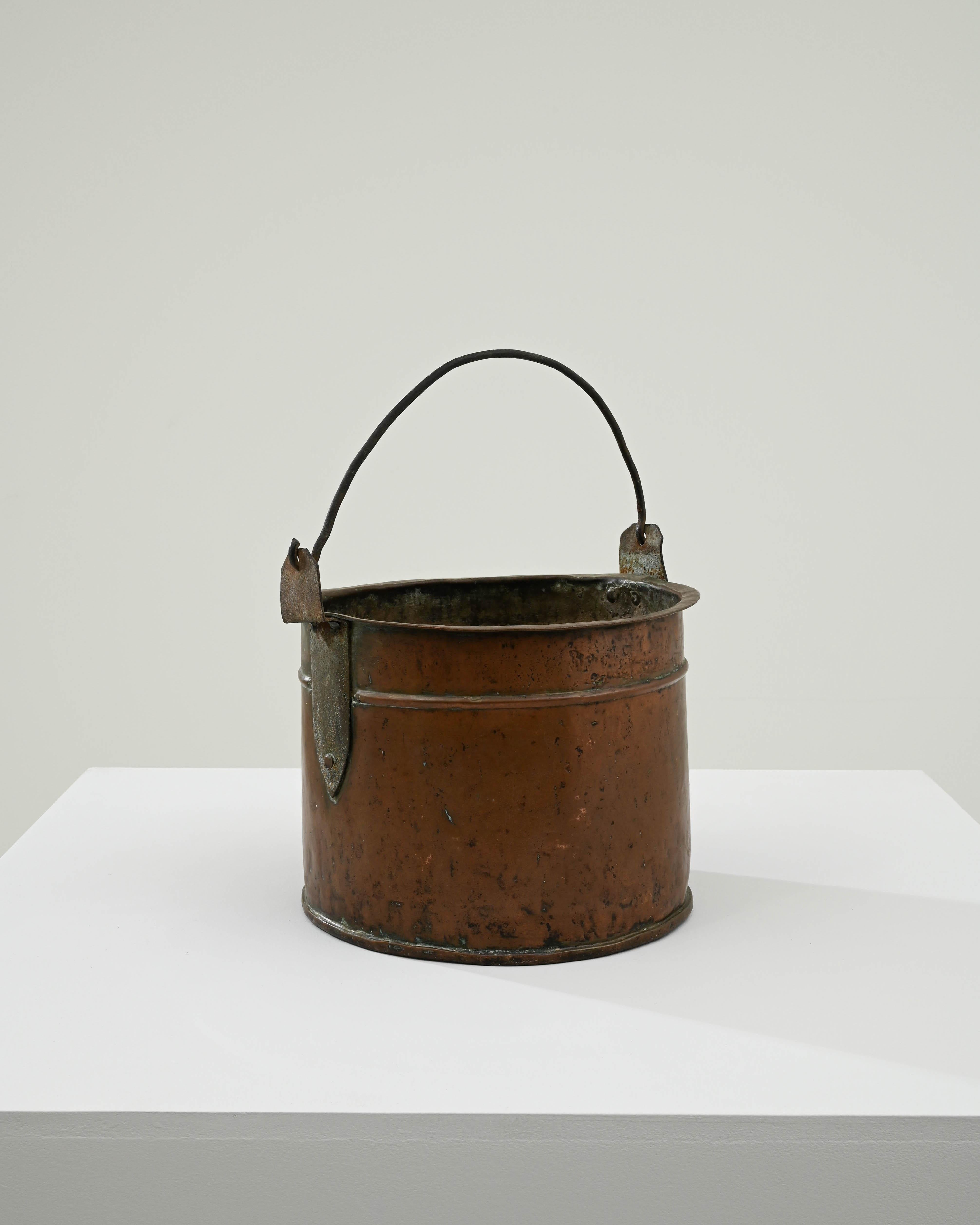 Enrich your kitchen décor with the timeless allure of a 19th-century French copper bucket. The exquisite hue of this bucket tells a tale of its age, showcasing a captivating patina that only time can bestow. Its copper complexion, beautifully