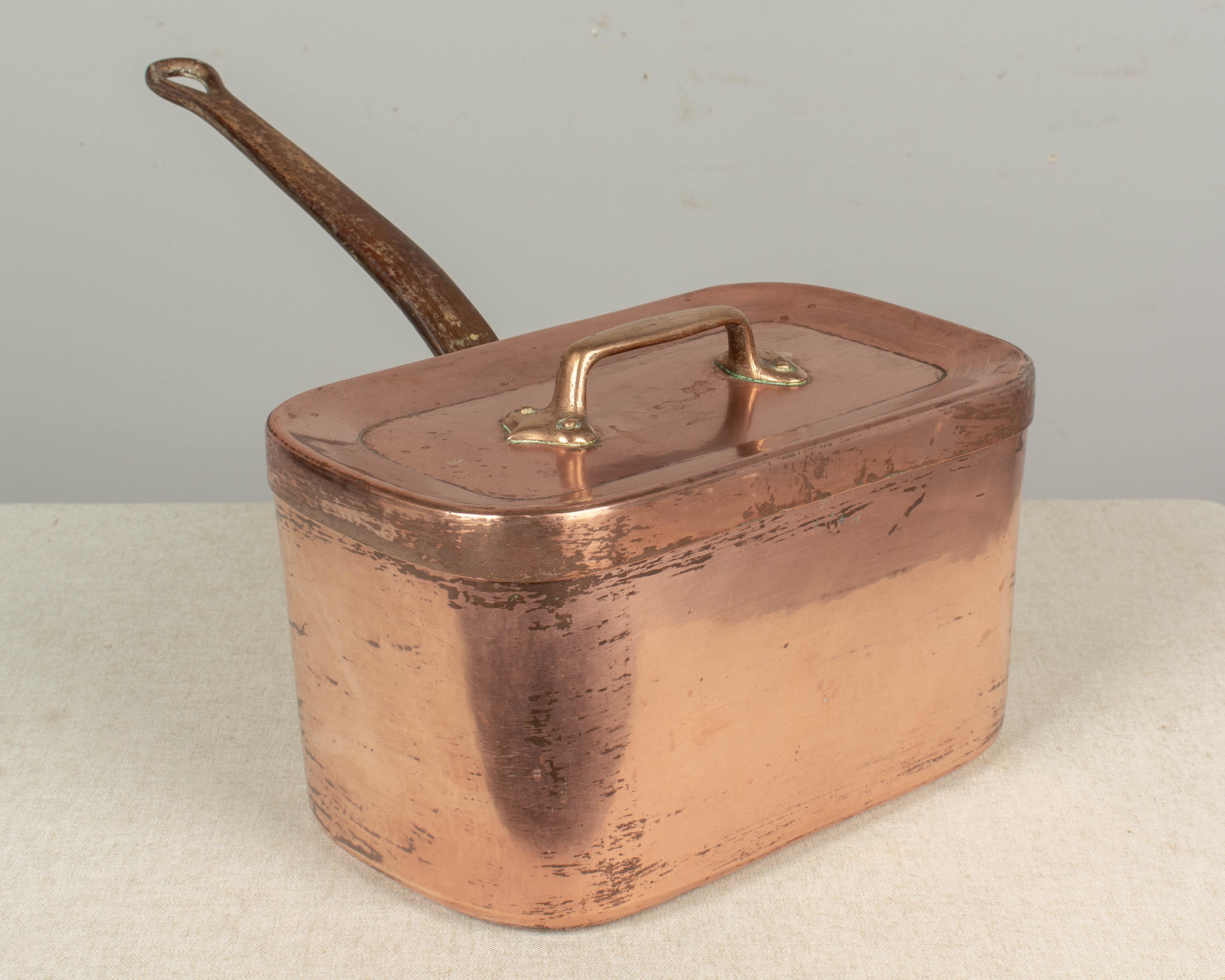 A large 19th century French copper daubiere or braiser pot. A good quality, handmade heavy pot with visible brass castellated or cramped seam on the side. Tight fitting lid with riveted handle. Long, thick cast iron handle, securely afixed with