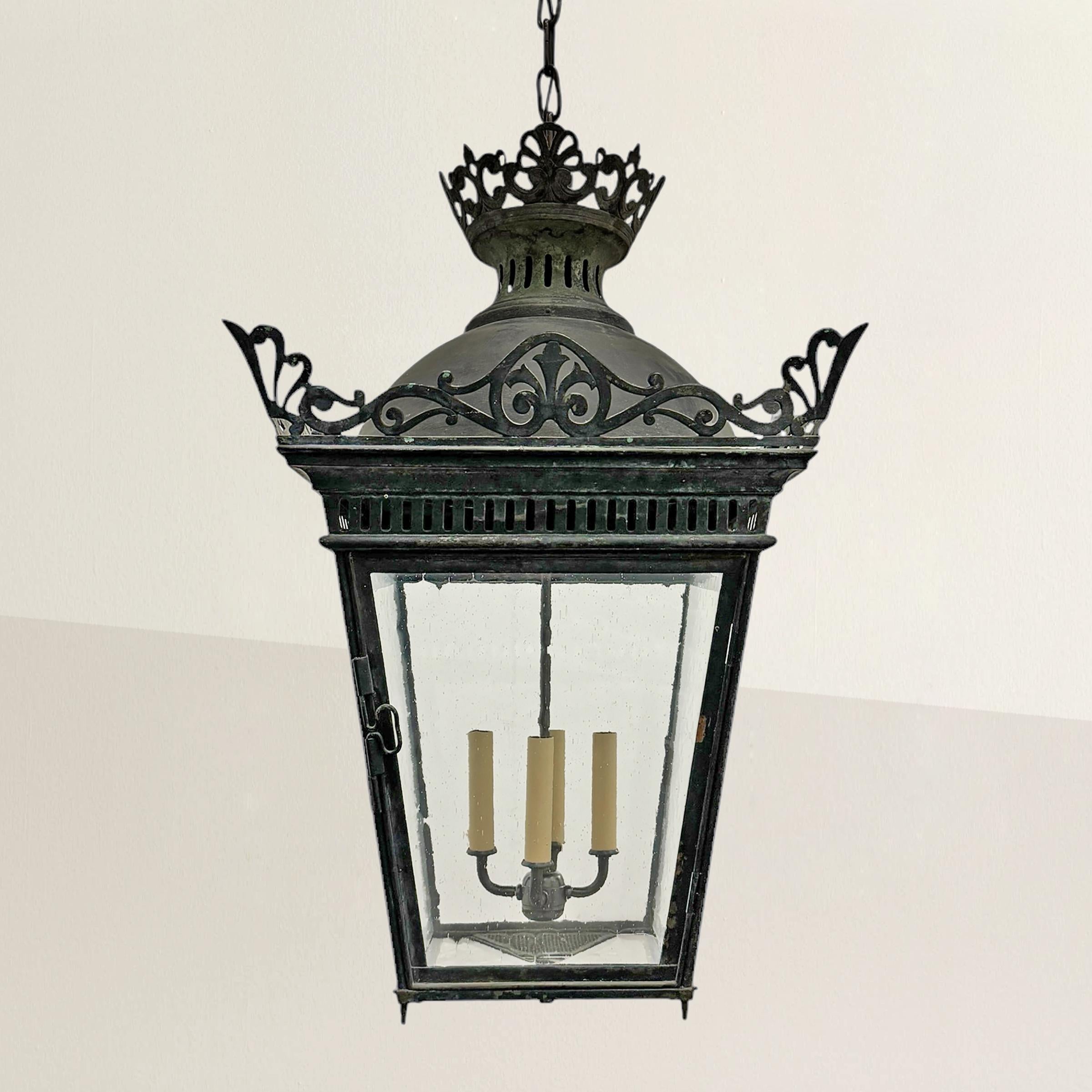 This 19th-century French copper street lamp, once perched atop a city post, has been masterfully transformed into a dramatic hanging lantern. Its patinated copper frame exudes shows centuries of exposure to the elements, while a beautifully detailed