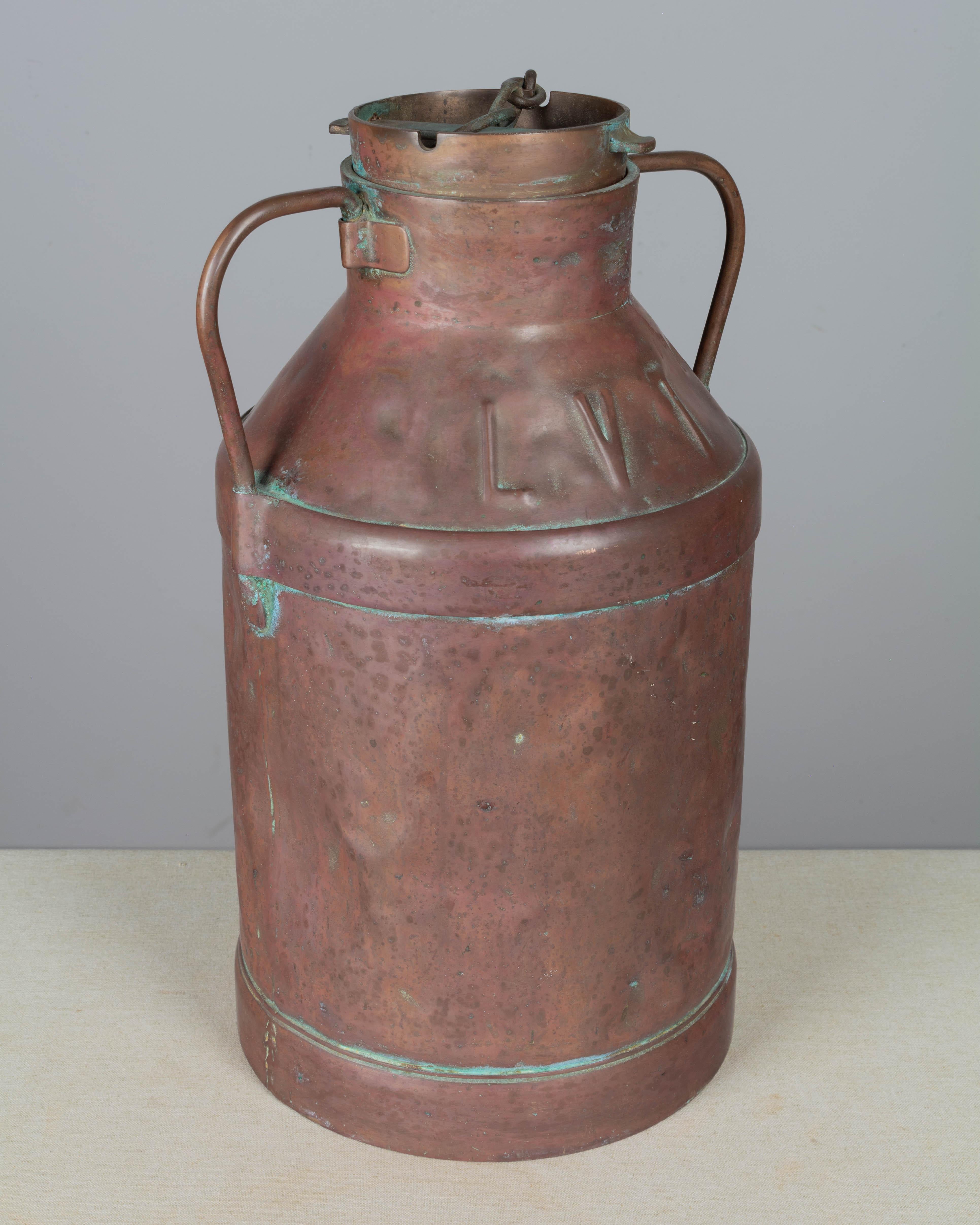 Una lattiera o brocca di rame francese del XIX secolo, con doppio manico e coperchio fissato con una corta catena. Grande, pesante e ben utilizzato con superficie ammaccata. Bellissima patina calda e invecchiata con ossidazione blu-verde sulle