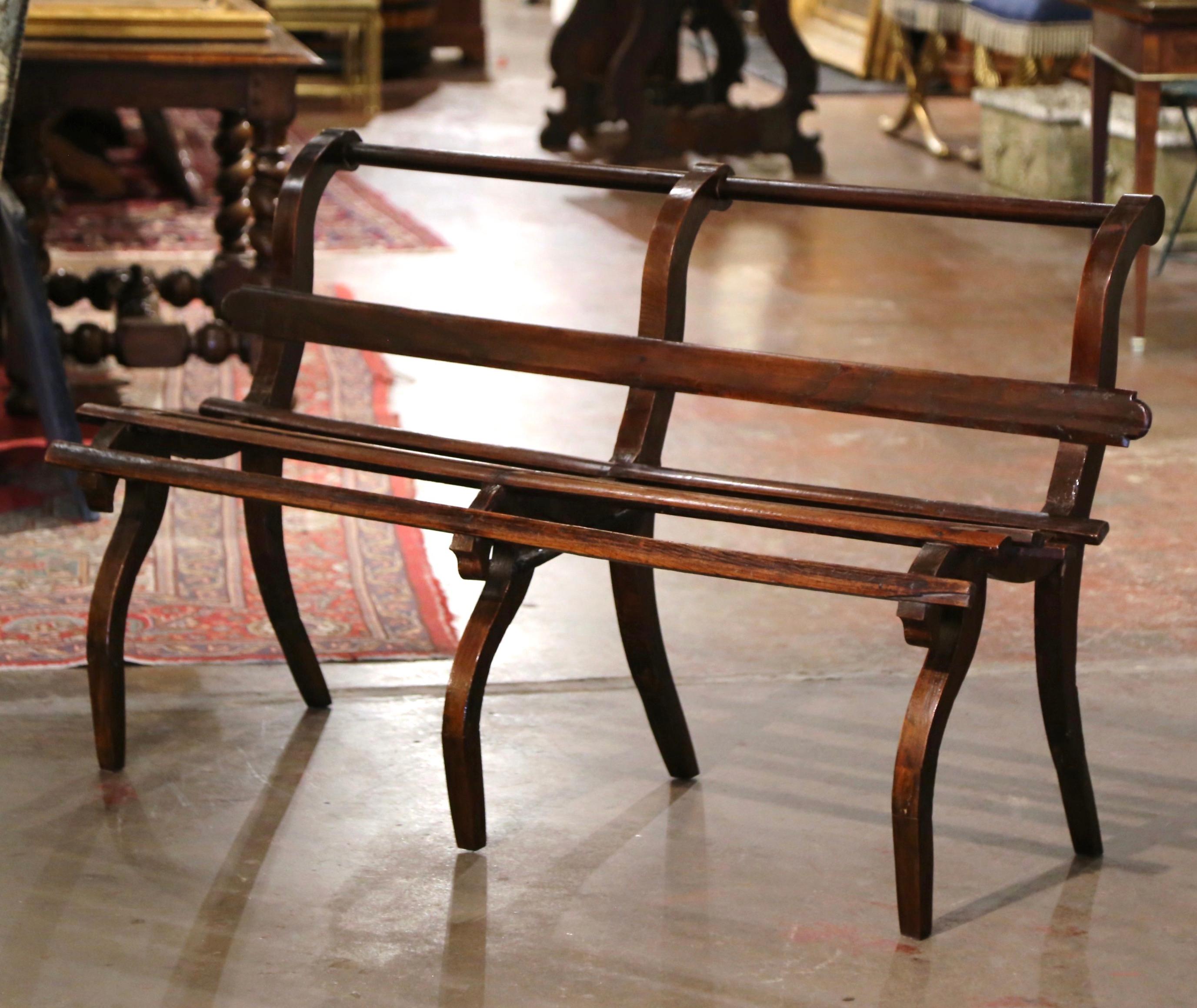 Crafted in France circa 1880 and made of oak, the antique bench stands on six curved legs and features four slat panels on the seat and a single slat across the open back embellished with turned top rail. The rustic bench is in excellent condition