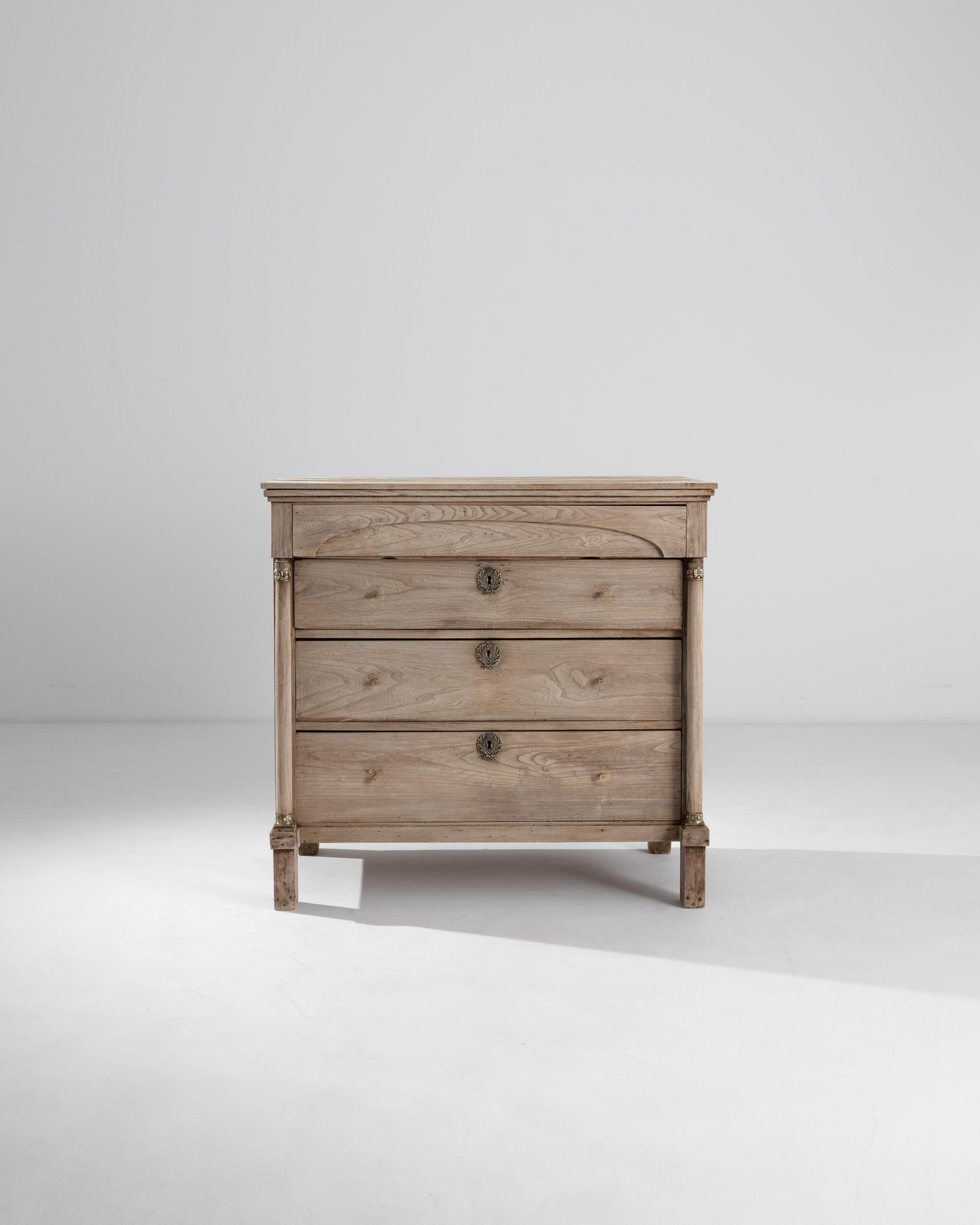 Rational and harmonious, this antique oak chest of drawers is a covetable find. Made in France in the 19th century, the neoclassical design reflects the restrained yet opulent tastes of the Napoleonic period. Carved pilasters, adorned with elaborate