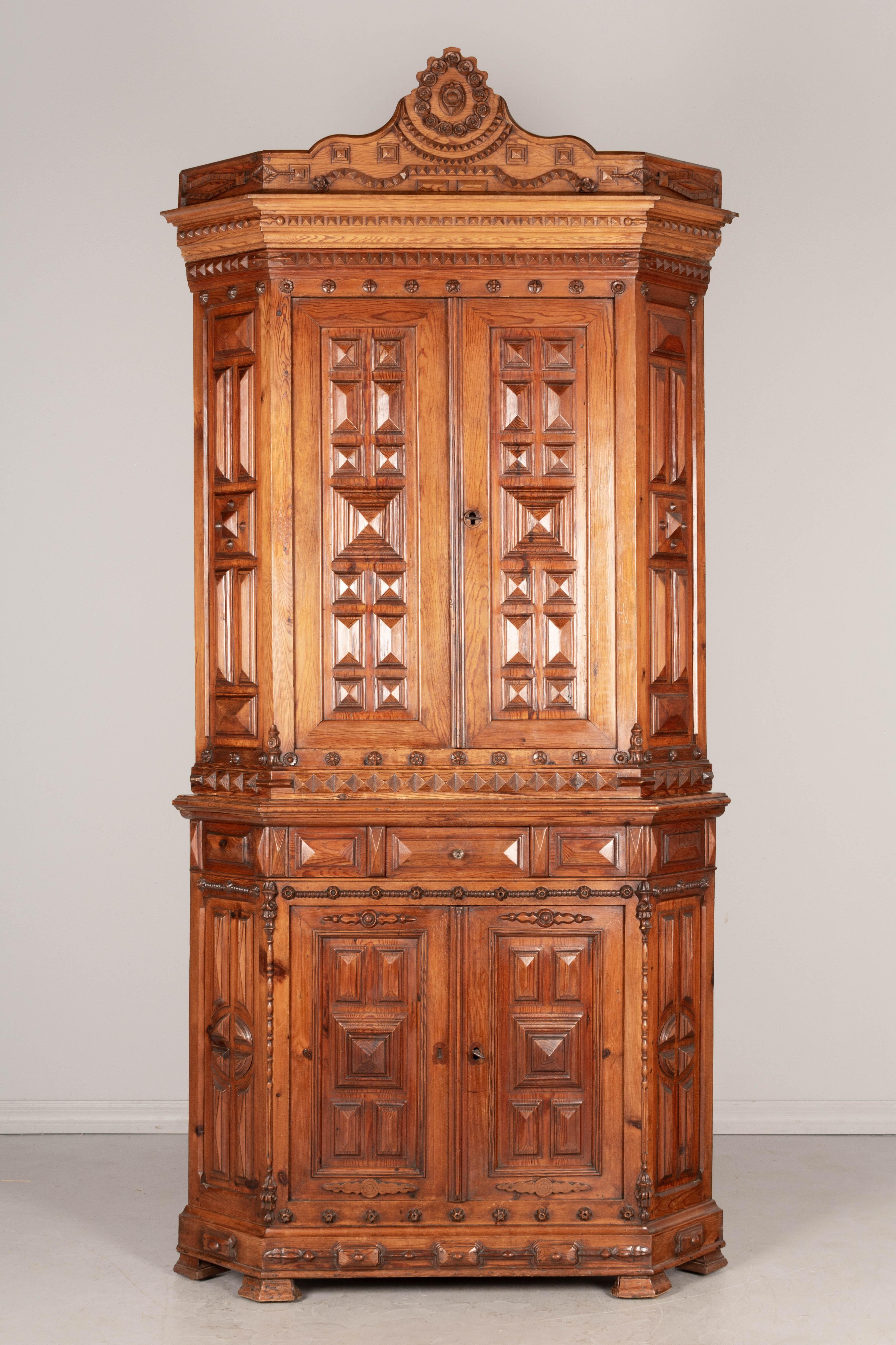 A fine 19th century French Art Populair, or Folk Art, corner cabinet from Normandy. Made of pitch pine with bold geometric carved panels. In three parts: the bottom has a small dovetailed drawer and one interior shelf, the top cabinet has two