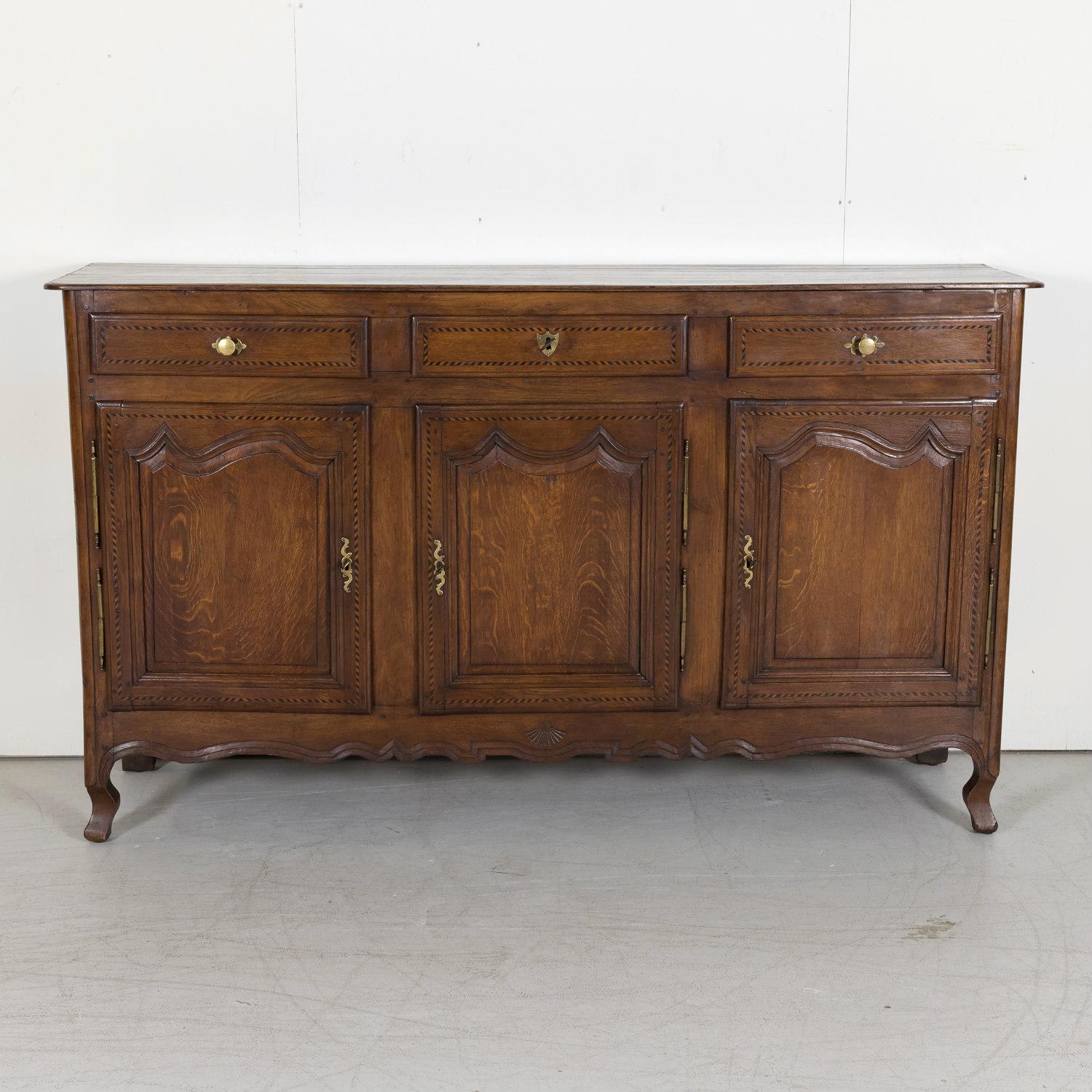 19th century French Country Louis XV style carved enfilade buffet handcrafted of old growth French oak and ebonized marquetry near Caen, a port city and capital of the department of Calvados in northern France's Normandy region, circa 1850s. This