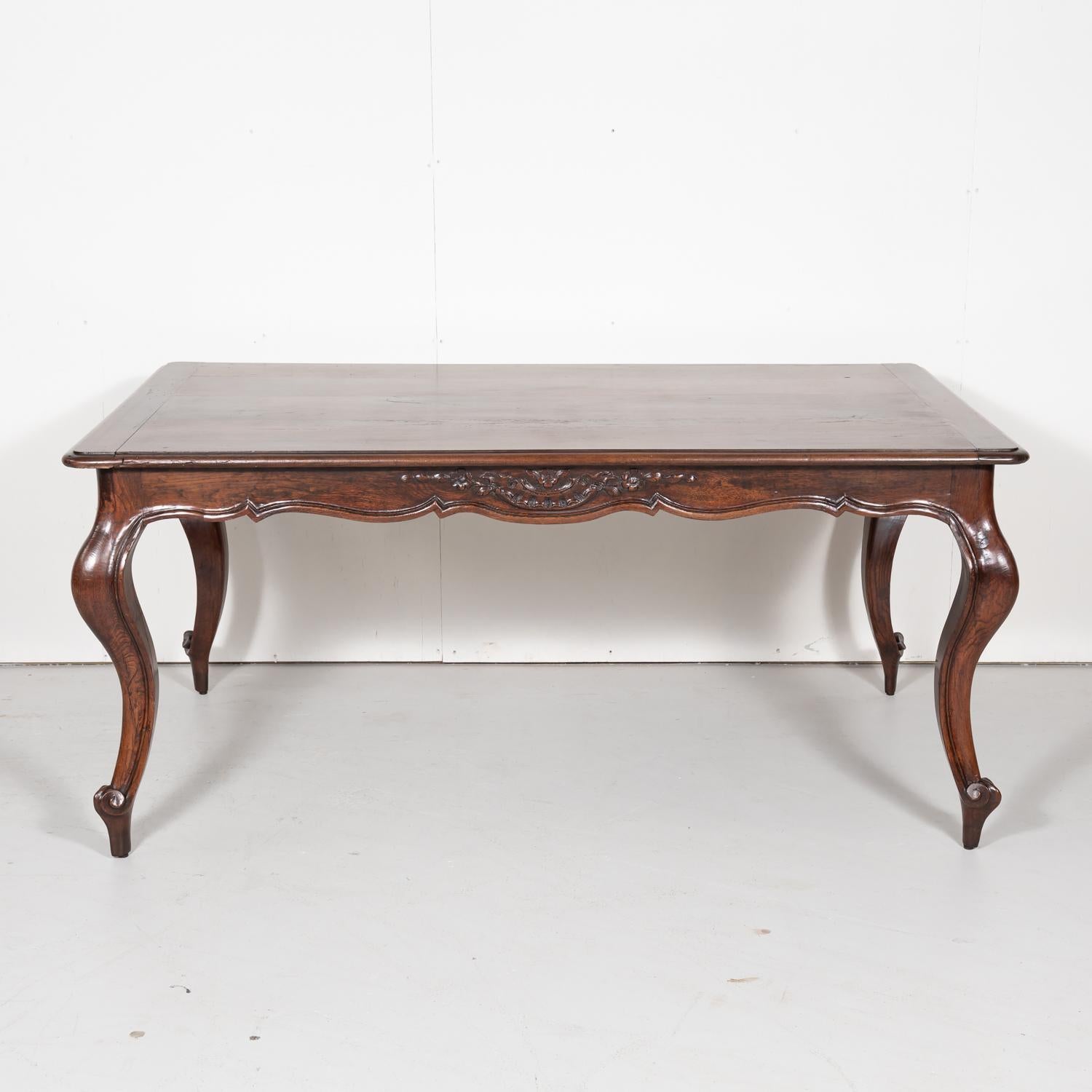 Charming 19th century French Country Louis XV style walnut farm table hand crafted by skilled artisans in the South of France near Nimes, circa 1890s. Having a moulded edge plank top with a wonderful grain above a finely carved scrolled apron