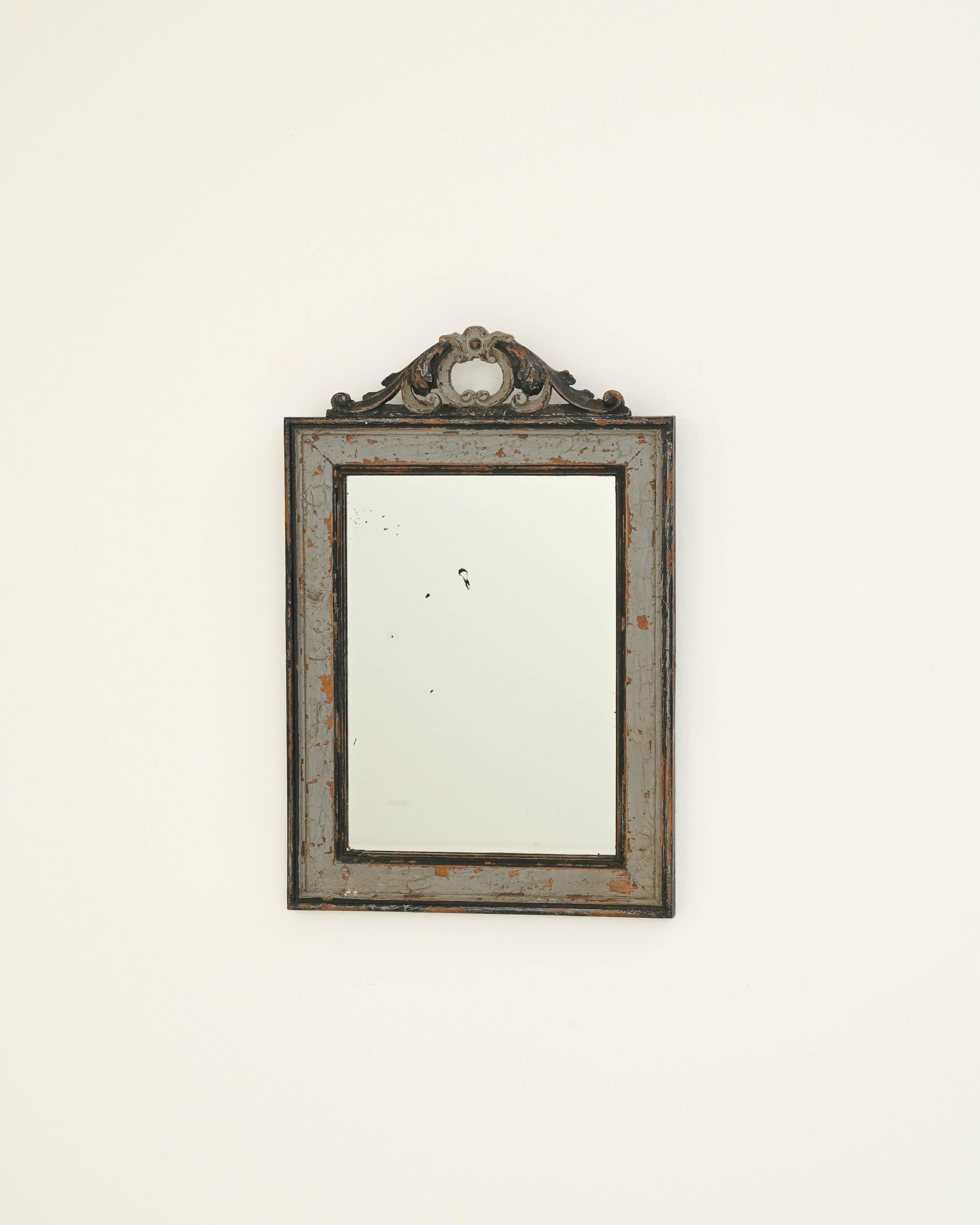 Displaying a gracefully weathered gray patina that delicately peels away, forming intriguing vein patterns, this 19th-century French-looking glass embodies the timeless elegance of aged wooden frames. The mirror is adorned with a sophisticated