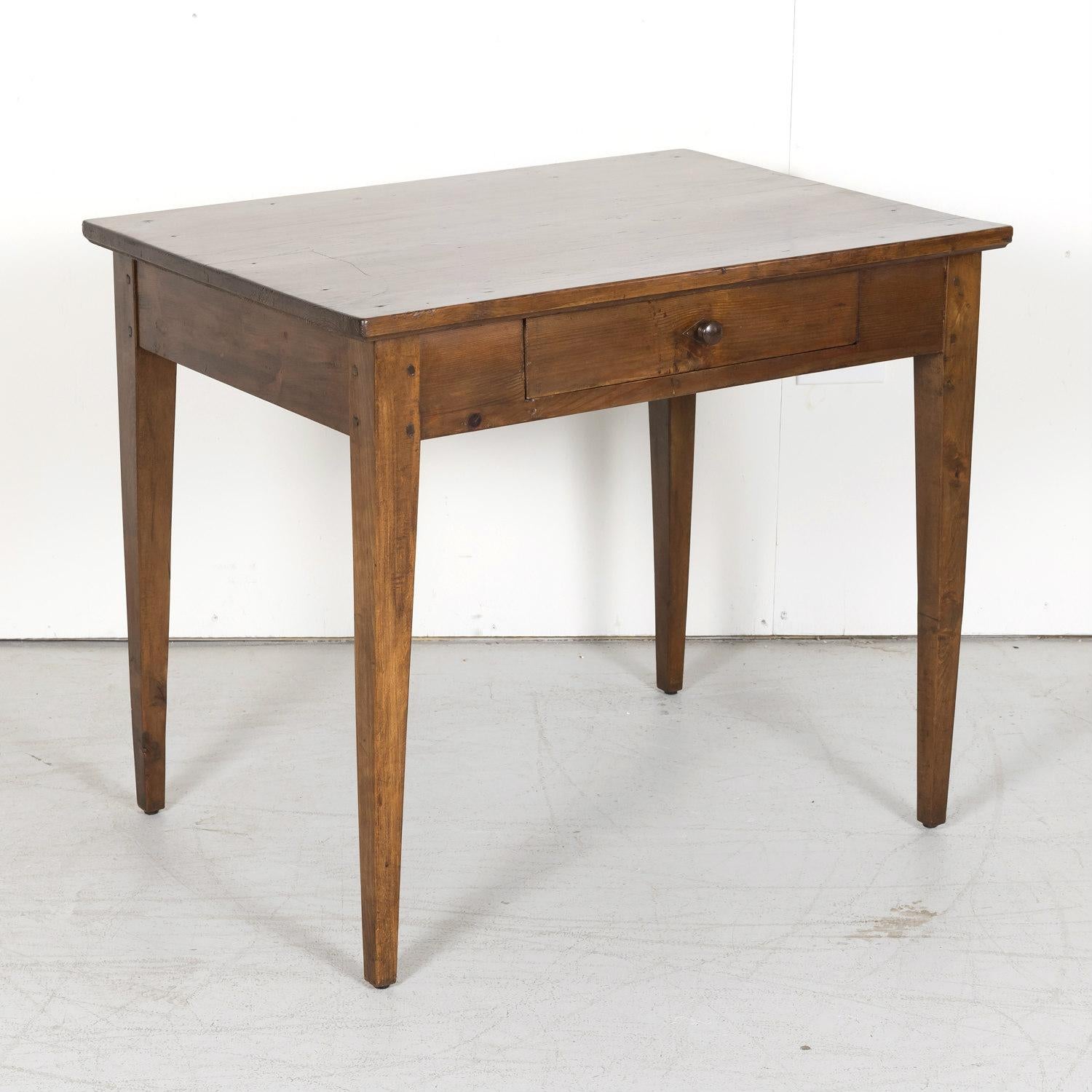 A rustic 19th century Country French side table or work table handcrafted of pine in Provence, circa 1890s, having a rectangular plank top above a single drawer with wooden knob. Raised on square tapering legs. Original patina.

Dimensions:
H -