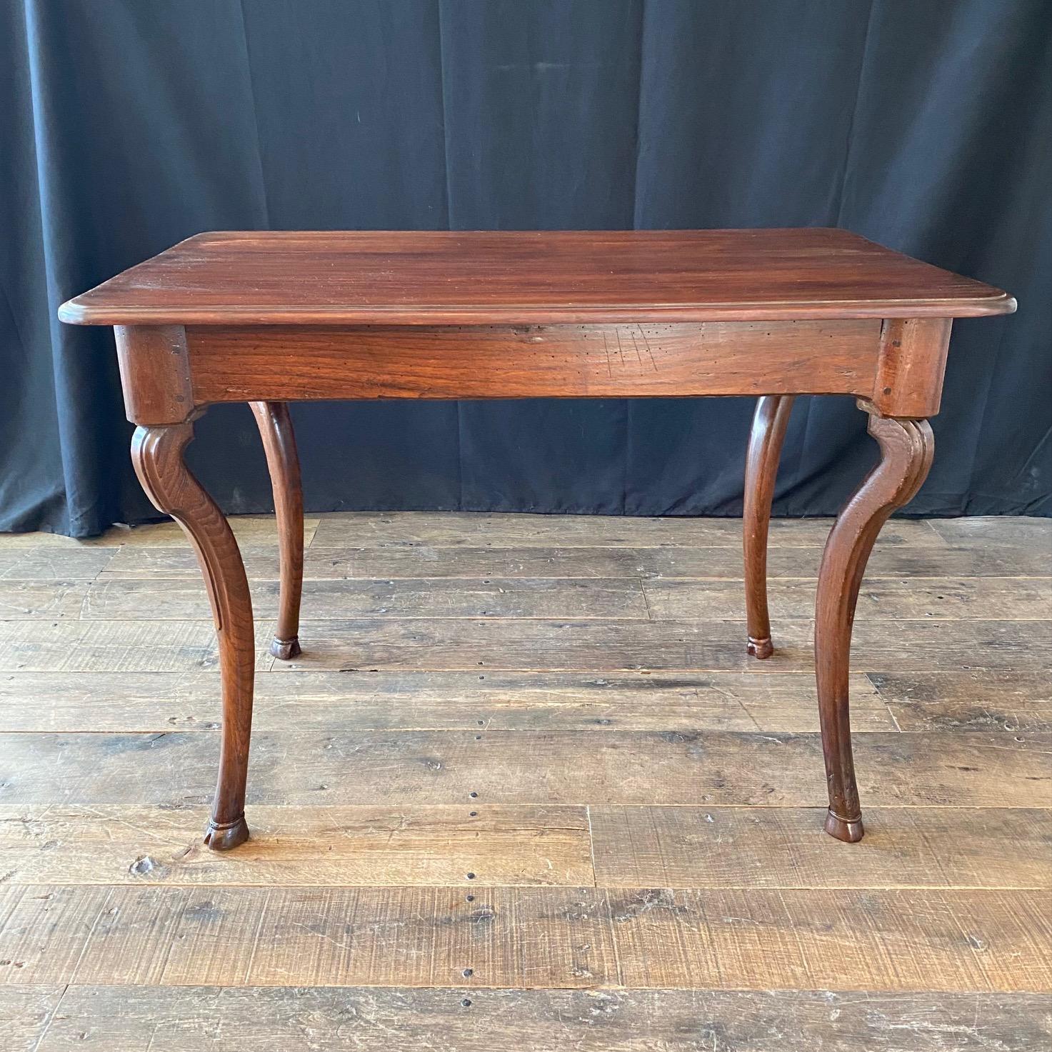 Country French walnut desk or side table with hoof feet and one wide front drawer. This smaller scale desk can be used in a variety of settings, or as a side table. Drawer shows evidence of its age; there is ink from an inkwell that has spilled