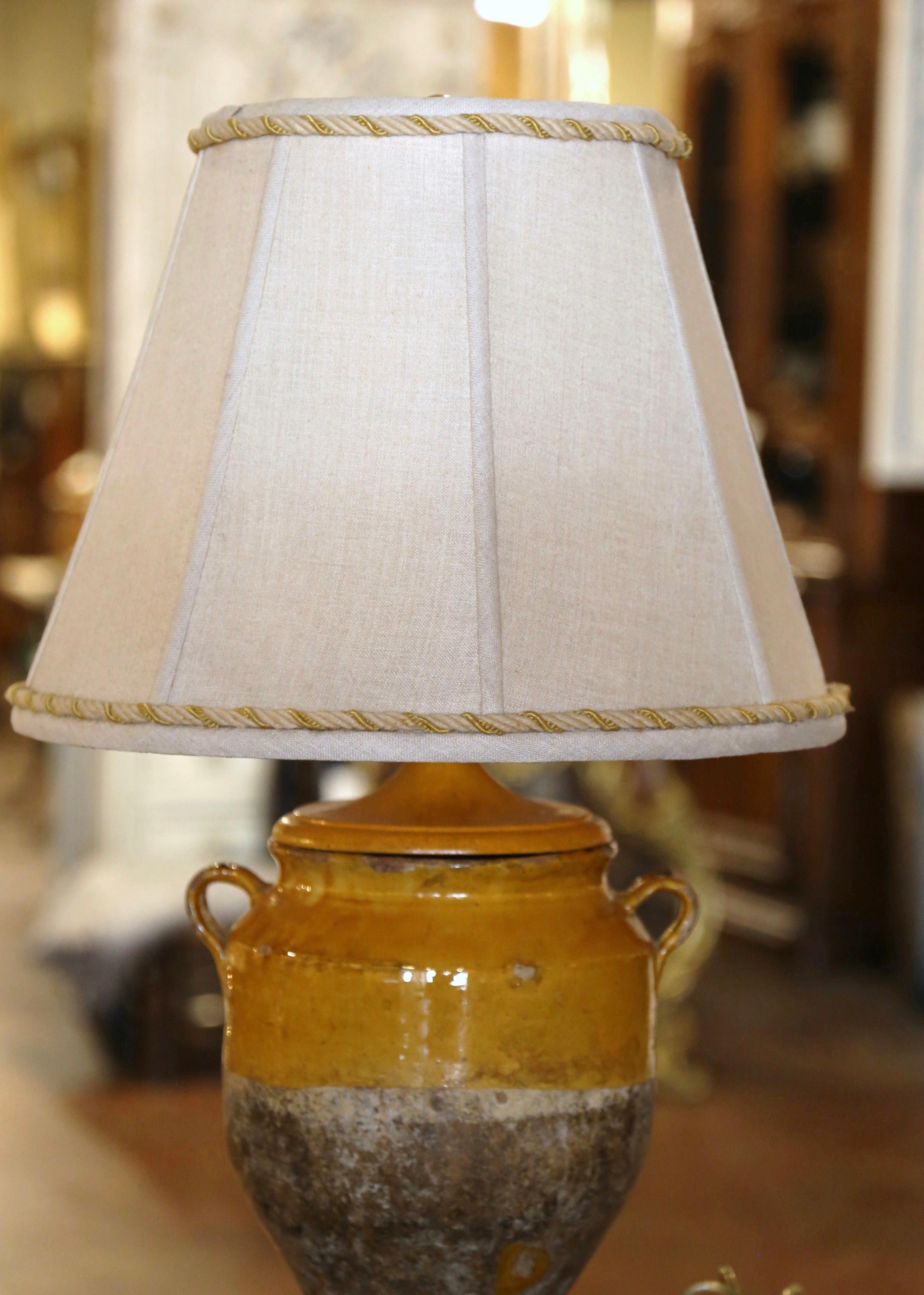 Bring a Country French look to your house with this elegant confit pot from the Perigord, converted into a table lamp. Standing on painted wooden base, the lamp is hard wired and dressed with a custom shade. Made of earthenware, these traditional