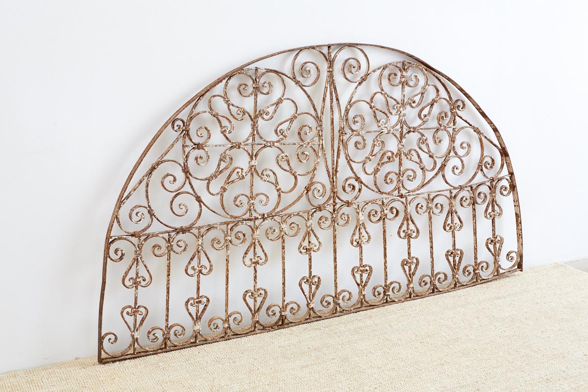 Decorative 19th century French wrought iron transom grille made in the Art Nouveau taste. Features a demilune form with scrolled circles and grates. Very solid and heavy with a beautiful distressed patinated metal finish and old paint remnants.
