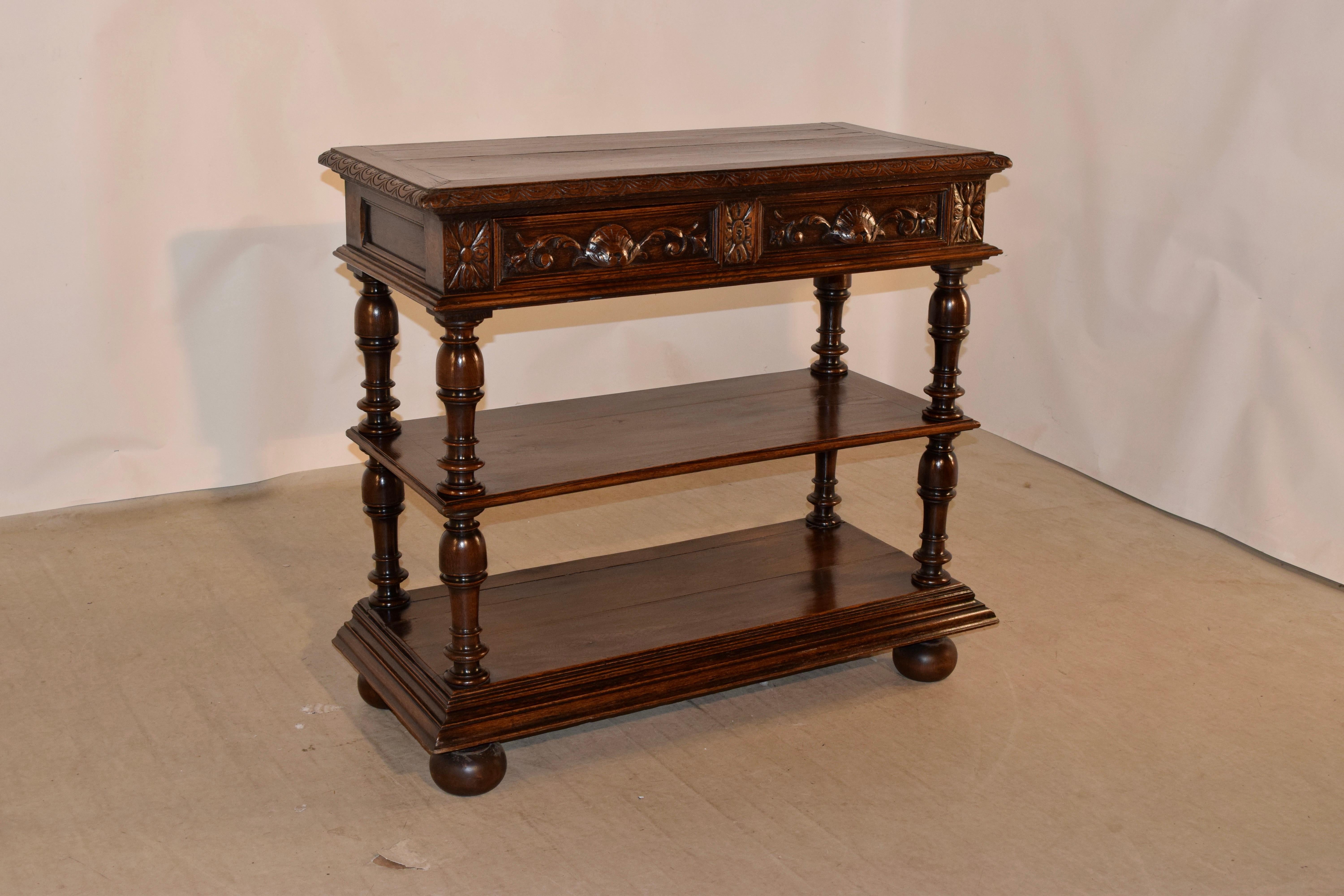 19th century French dessert buffet made from oak. The top is banded and has old repairs from shrinkage. The apron is paneled on the sides and contains two front drawers, over two shelves, separated by wonderfully turned shelf supports. Resting on