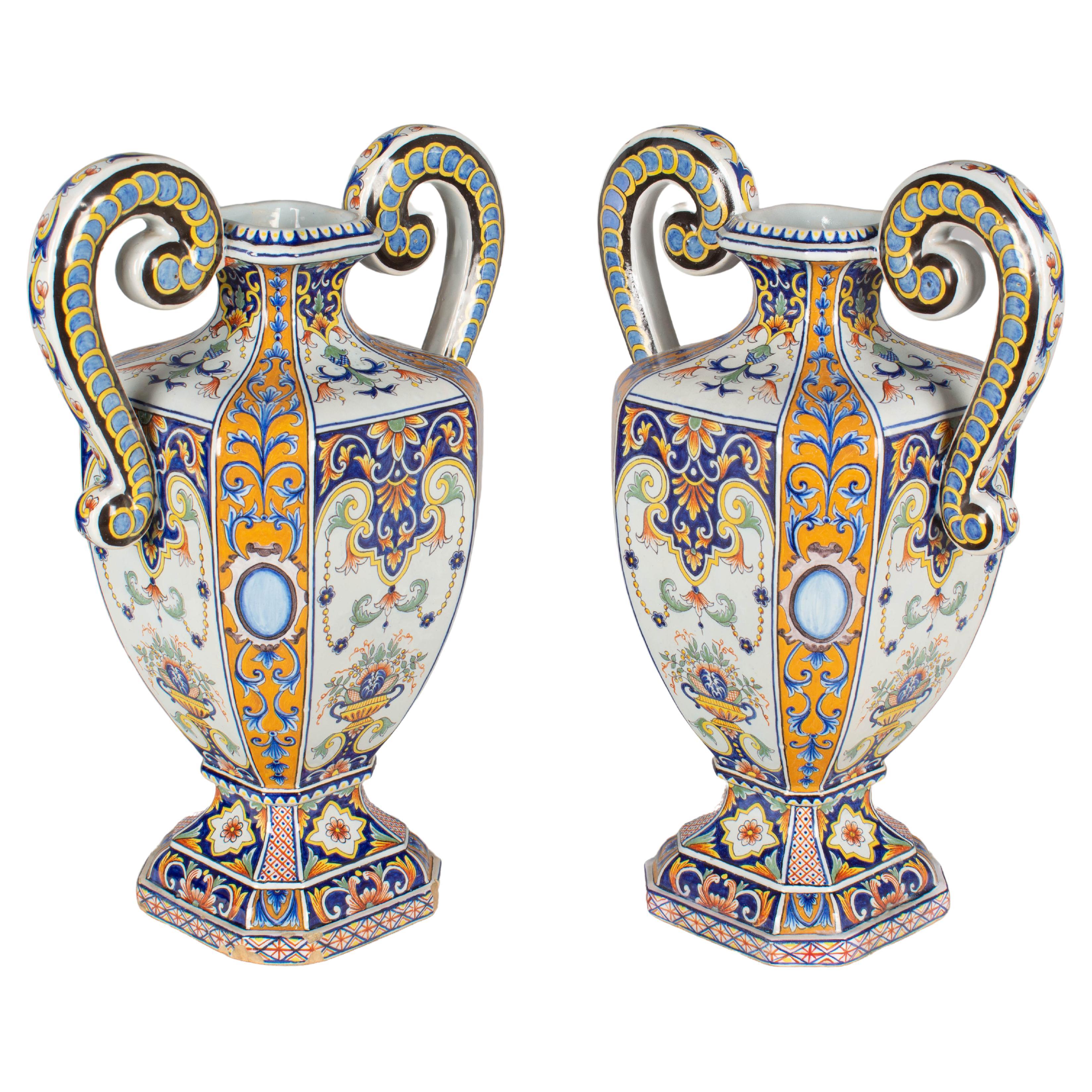 A pair of 19th century French Desvres faience urn form vases with large double handles. Beautiful hand-painted floral decoration in the traditional colors of blue, orange, yellow and green. Fourmaintraux-Courquin mark on underside: F.-C. Circa