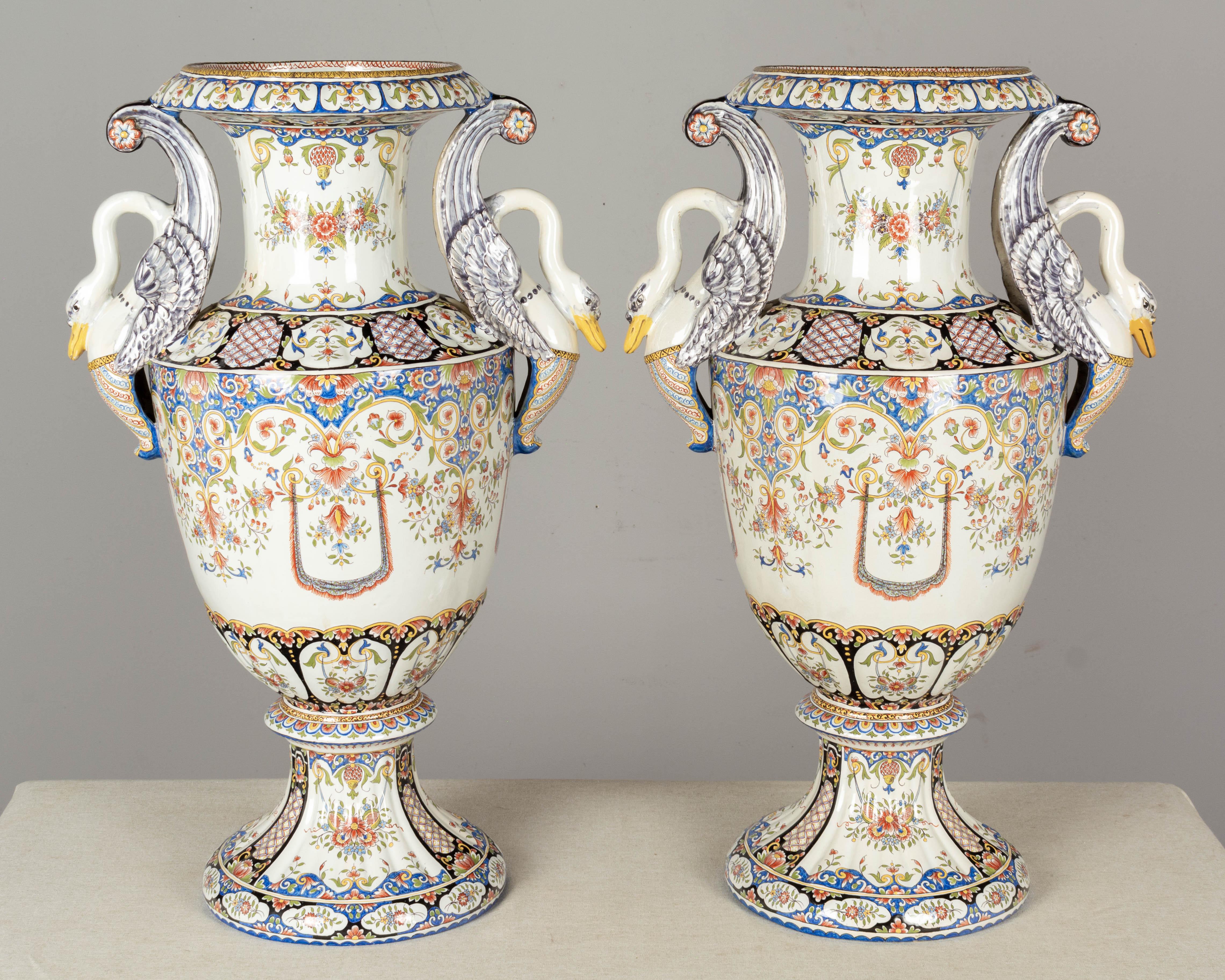An exceptional pair of large 19th century French faience urns from Desvres, by Fourmaintraux-Freres. Beautiful hand-painted floral decoration and sculptural swan handles. Elegant form with nice proportions. In almost mint condition with the beak of