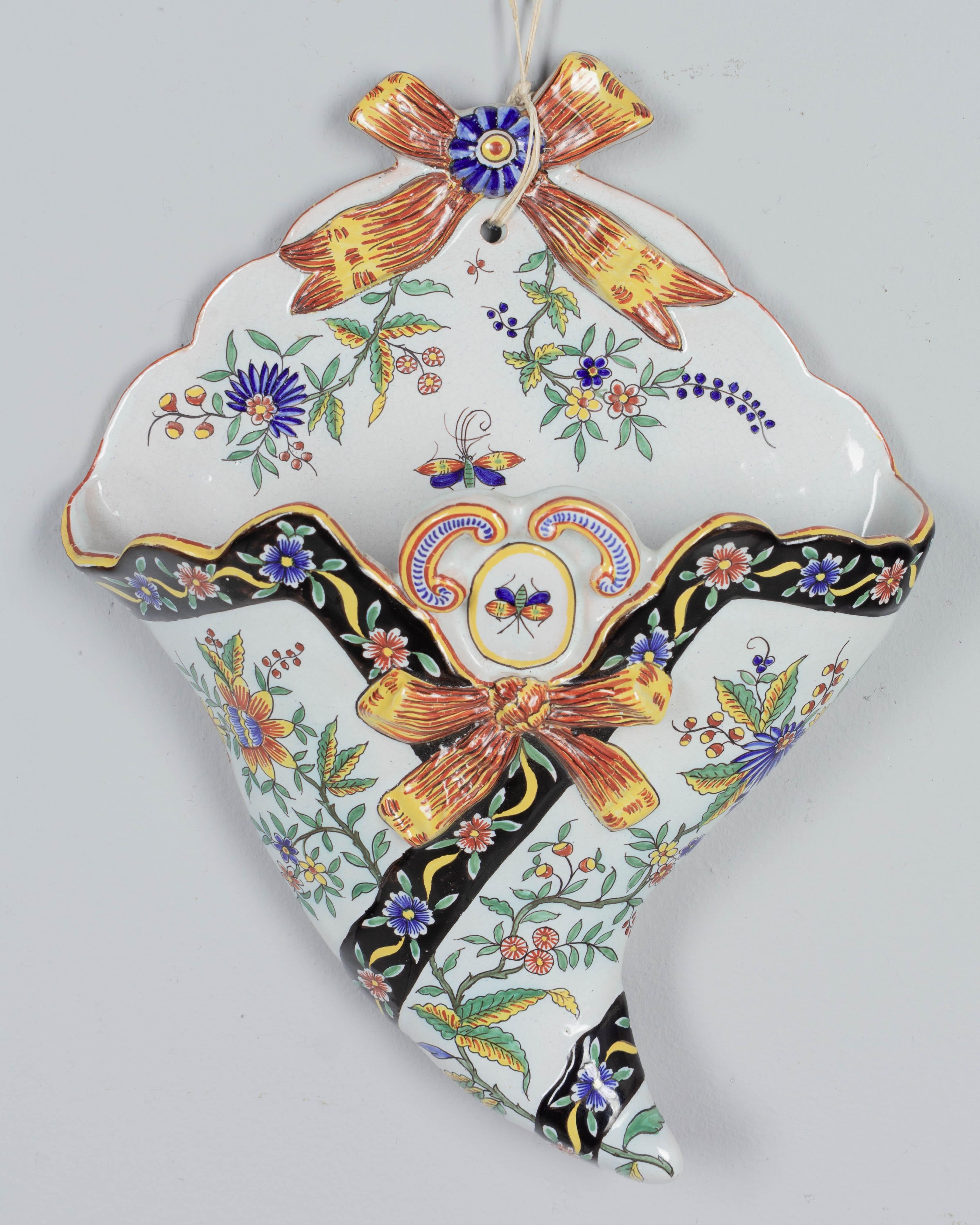 Pochette murale en faïence de Desvres du XIXe siècle, ou porte-fleurs en forme de cône, avec décoration florale et rubans peints à la main. Marque du fabricant au dos : Fourmaintraux Courquin. Légère usure de la glaçure. Circa 1890-1900.
Dimensions