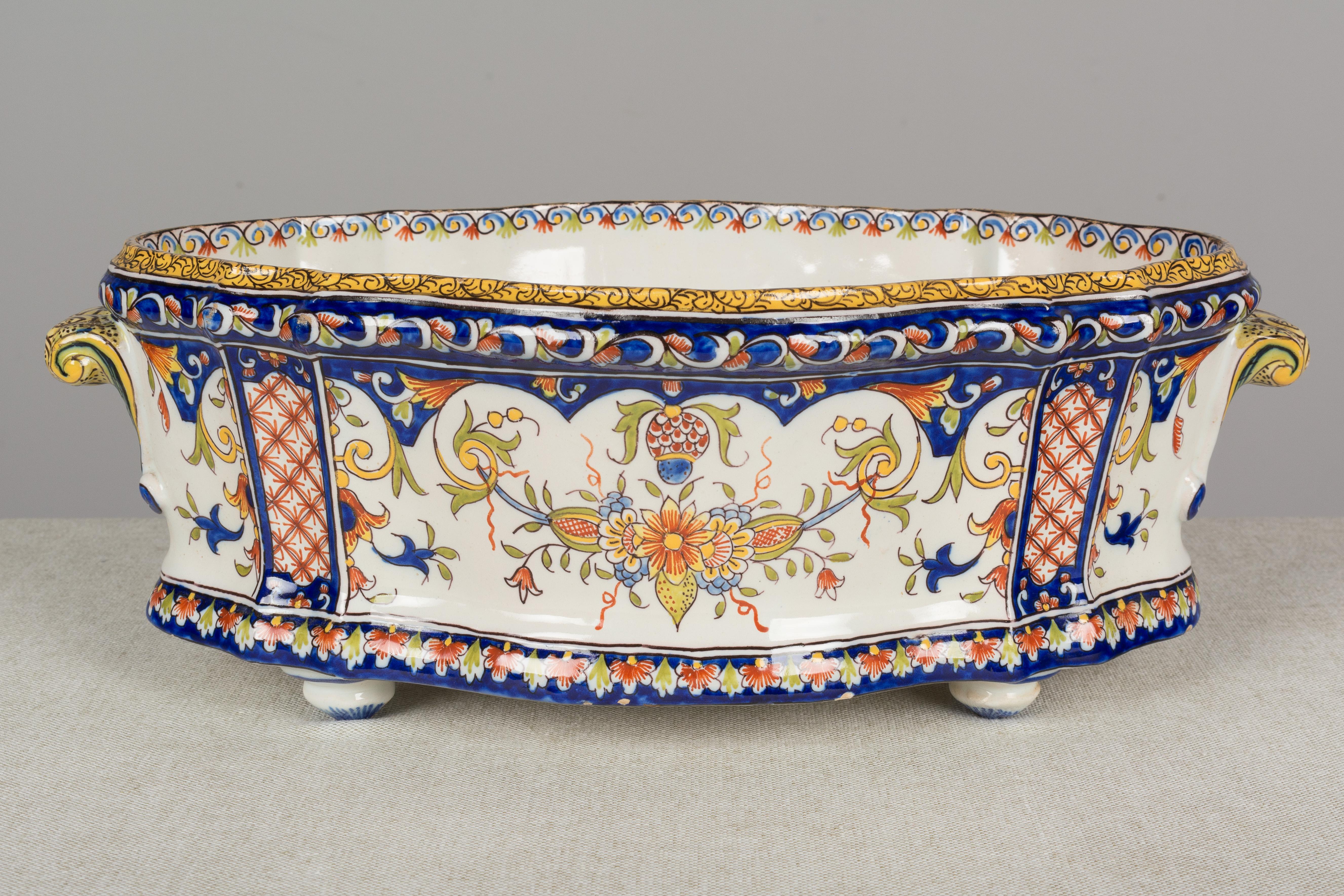 A 19th century French faience jardinière, or planter, from Desvres by Fourmaintraux Freres. Hand painted in typical floral design with beautiful vivid colors of blue green and yellow and red on white ground. Footed shallow bowl with oval shape and