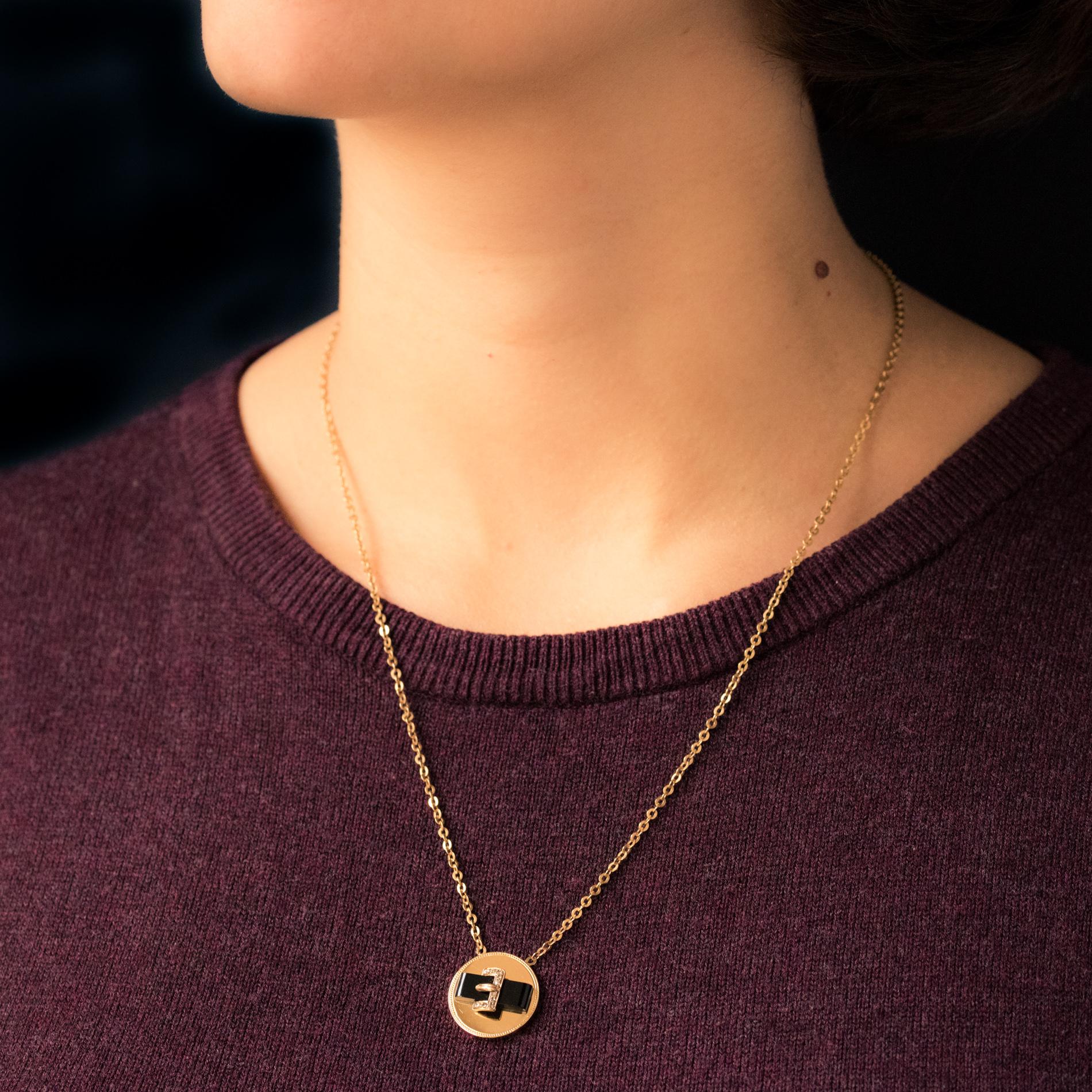 Pendant in 18 karat yellow gold, eagle's head hallmark.
Round shaped, this pendant features an onyx belt pattern with a gold buckle set with rose- cut diamonds. It is supported by a flat jaseron mesh chain. The clasp is a spring ring.
Total length: