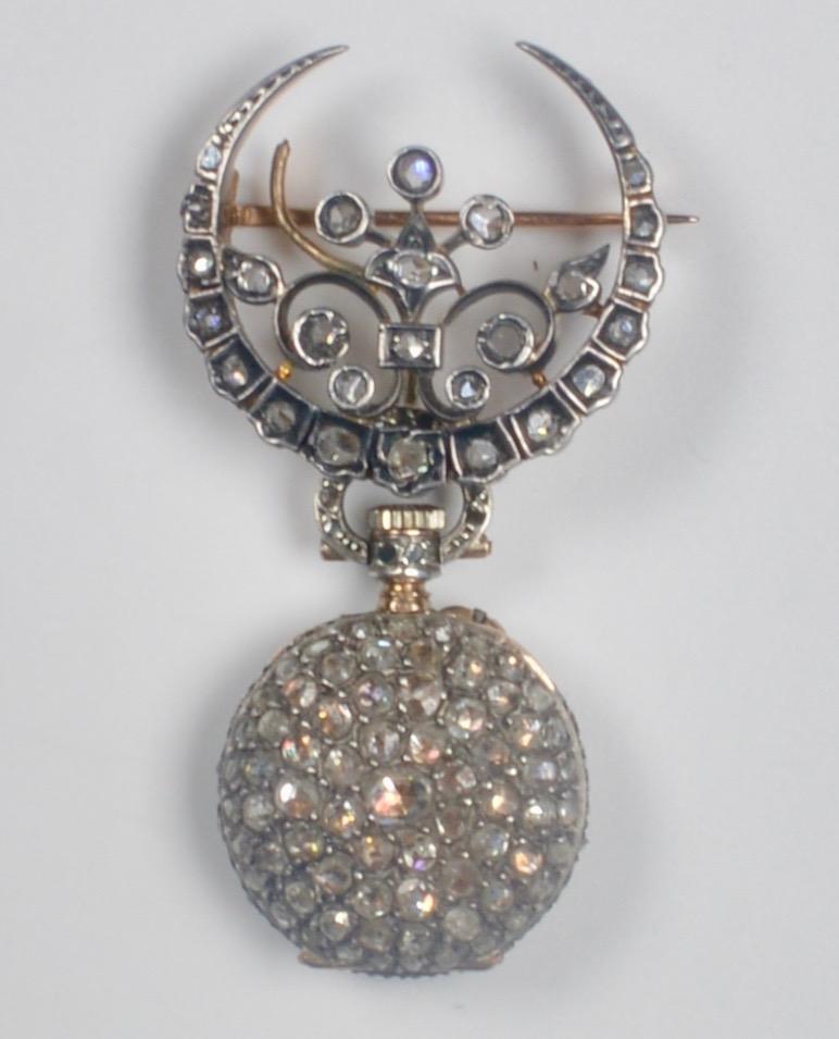 An exquisite late 19th Century French watch and watch pin brooch profusely set with rose-cut diamonds and mounted in 18 karat gold and silver. Swiss made movement 17 jewels. white enamel face and black numerals with silver hour and gold minute