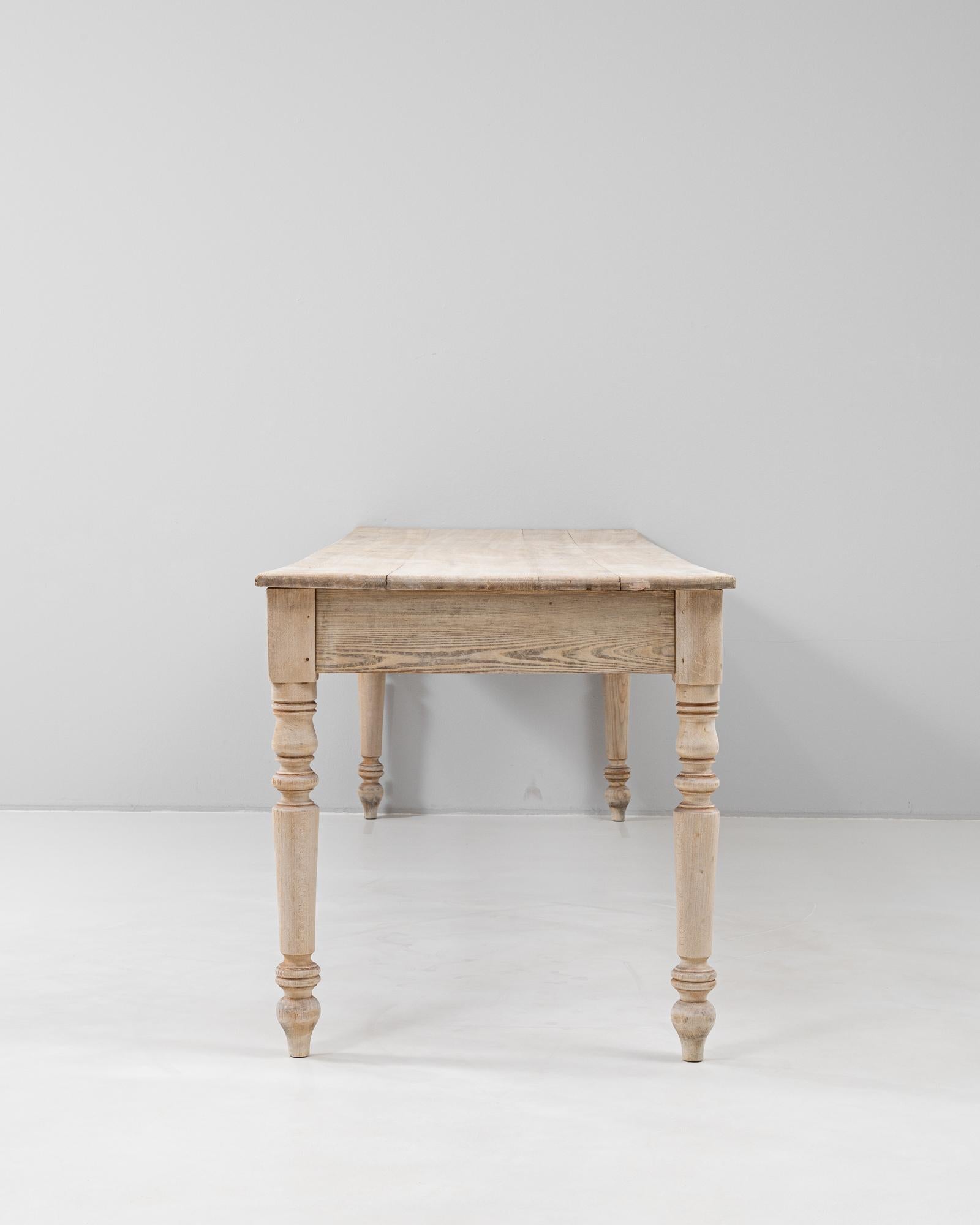 This 19th Century French dining table combines rustic charm with classic craftsmanship, featuring a long, subtly bowed top and beautifully turned legs. Crafted from solid wood with a bleached finish that highlights the natural grain, the table has a