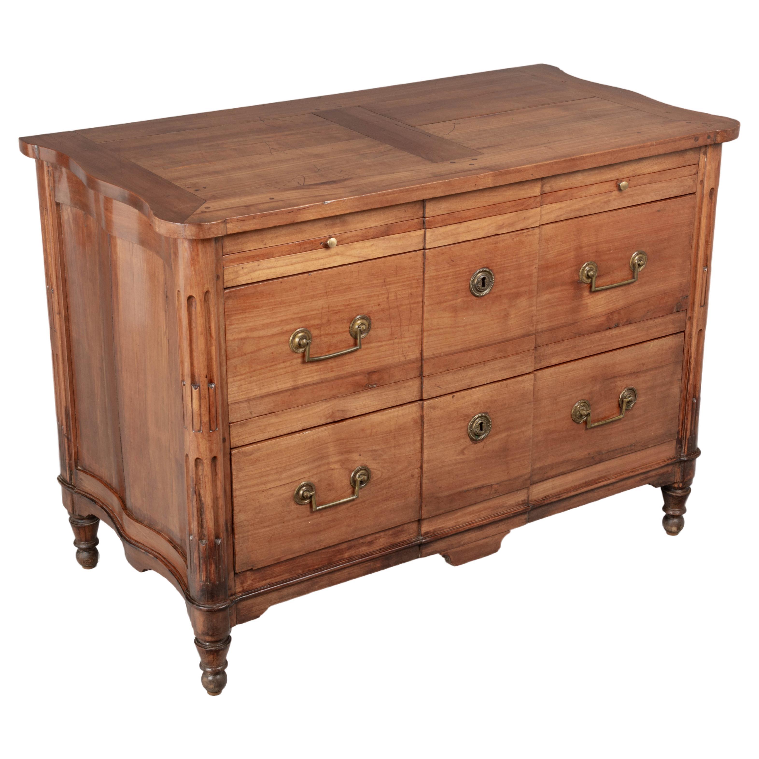An early 19th Century French Directoire Period commode made of solid cherry wood with yellow pine as a secondary wood. Unusual form with serpentine sides. Rounded fluted front corners with short turned tapered legs. A well-crafted chest with two
