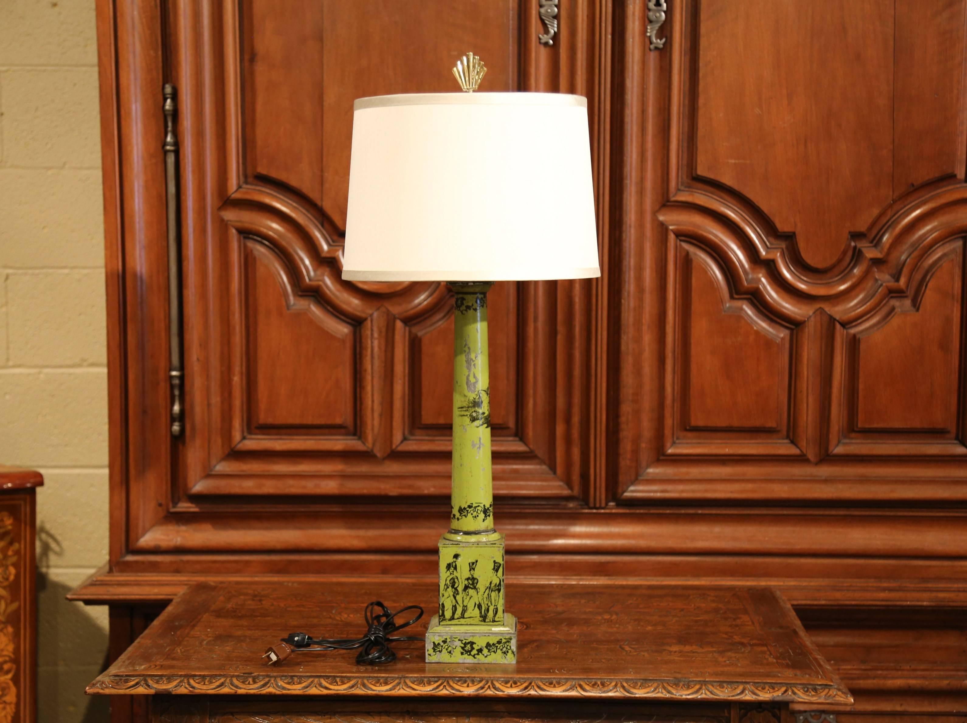 Décorez une table avec cette élégante lampe tole antique. Fabriqué en France vers 1840, ce luminaire au câblage neuf repose sur une base carrée surmontant une haute tige, et présente un décor de soldats et de feuillages peints à la main en noir sur