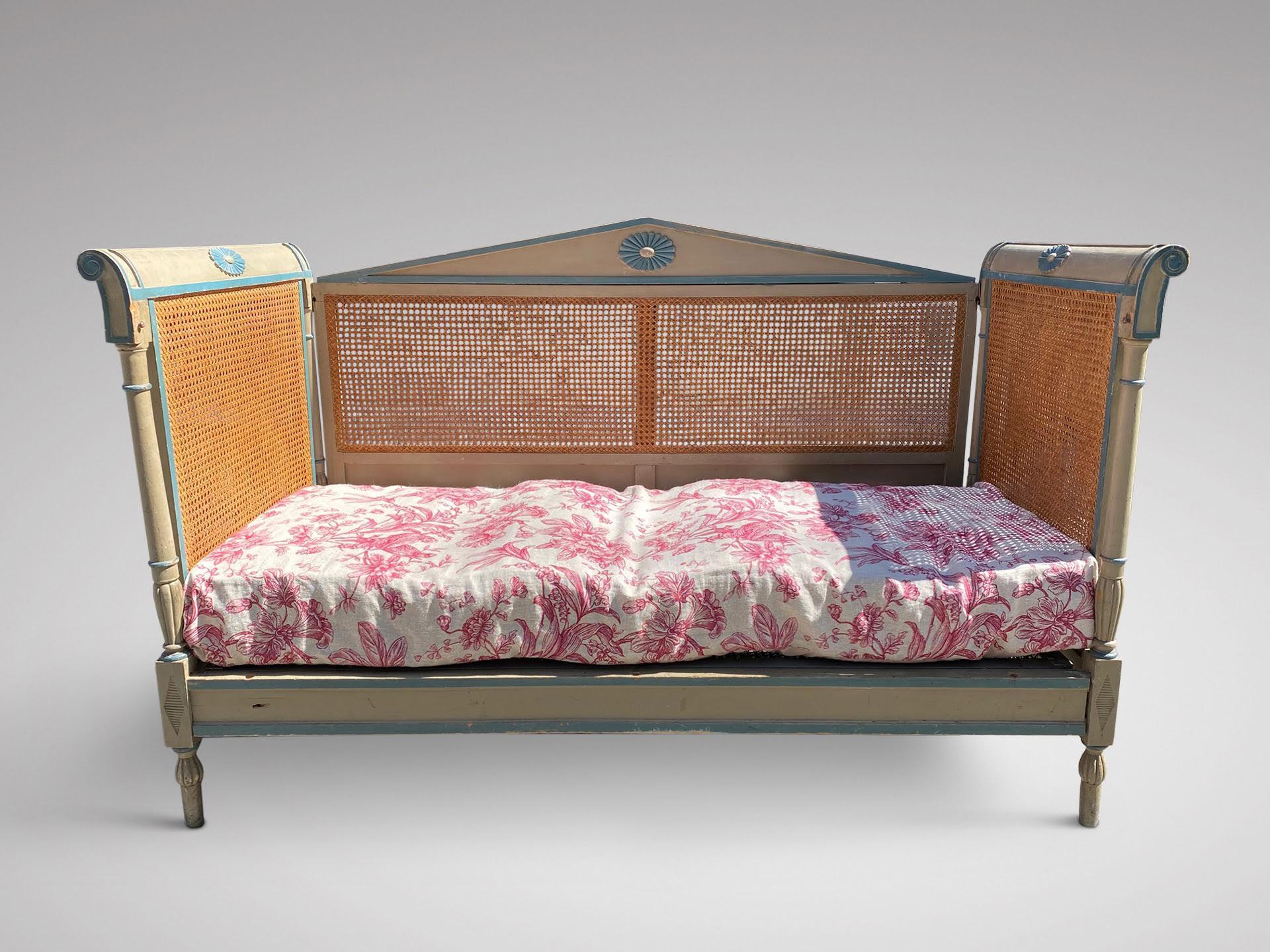 A late 19th century French Directoire daybed, the carved frame painted in green and blue and upholstered matress in toile de jouy. The metal base is supported on wooden batons which can be easily removed. All sides in original double cane work and