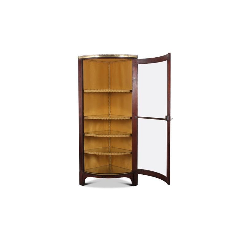 An unusual, French mid-19th century, mahogany-framed corner cabinet, or vitrine, the single door with original curved glass panels and brass trim and flanked by fluted pilasters. Pierced brass gallery top, circa 1850.



     