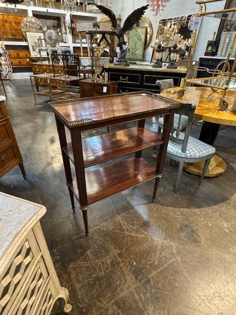 This 19th Century French Directoire Style Mahogany Etagere is a stunning piece of antique furniture crafted from mahogany with brass details. The etagere features a elegant and classic look. Perfect for displaying books, decorative items, or other