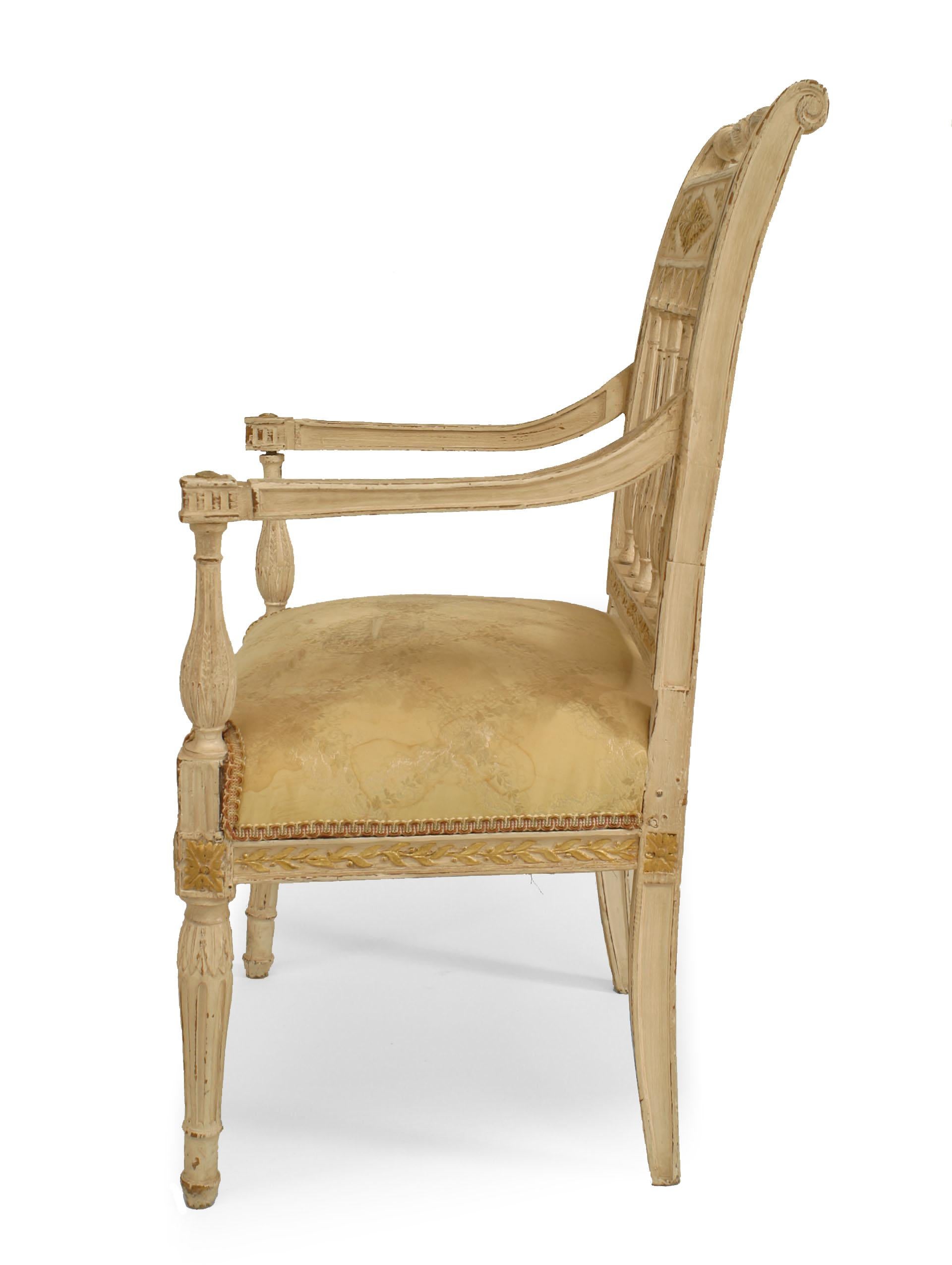 French Directoire white painted open arm chair with gilt foliate decoration and shaped fluted arms, legs, and open fluted columns on back.
 